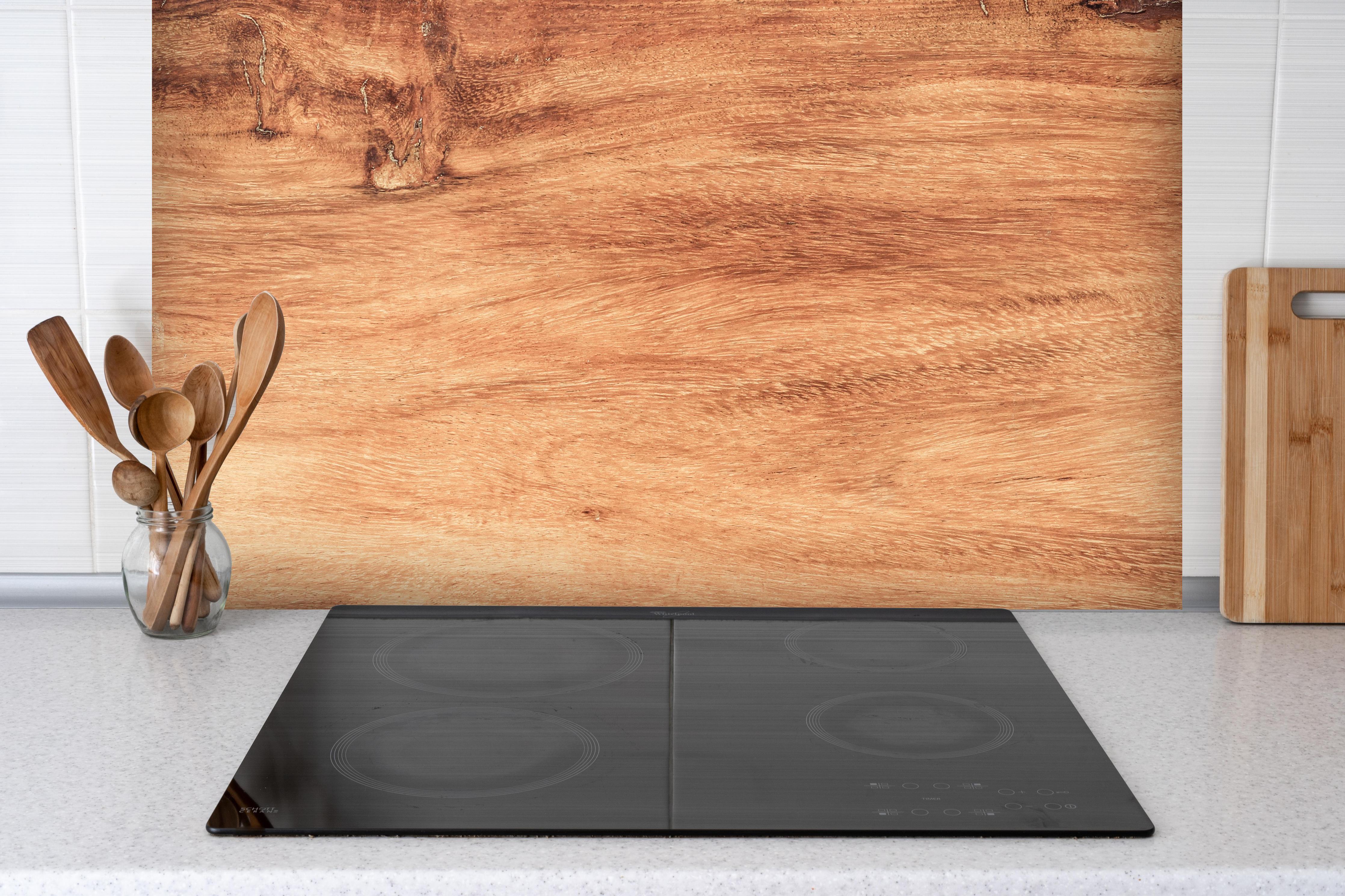 Spritzschutz - Teakholz mit natürlichem Muster hinter einem Cerankochfeld zwischen Holz-Kochutensilien