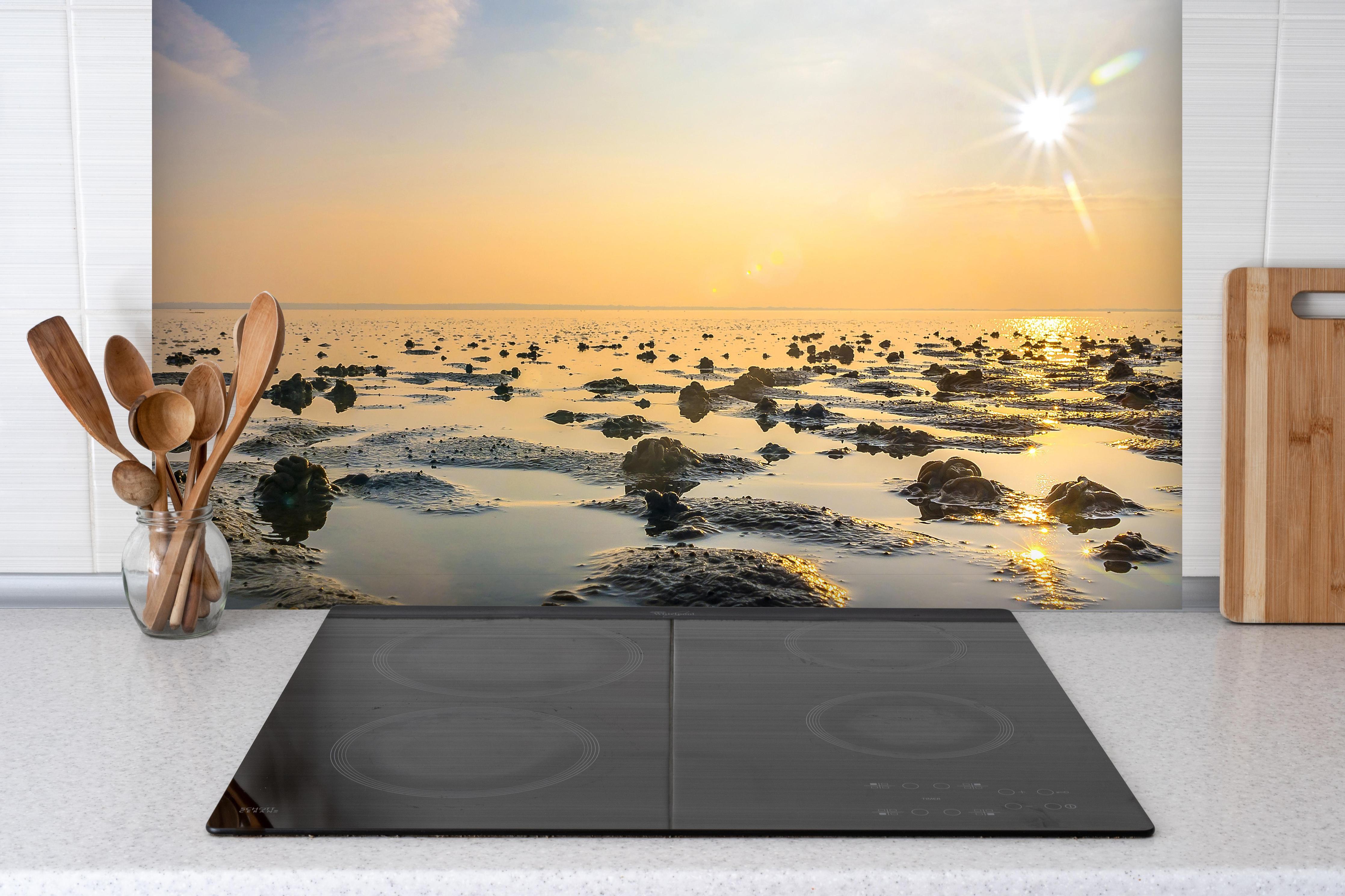 Spritzschutz - endlose Küste der Nordsee hinter einem Cerankochfeld zwischen Holz-Kochutensilien