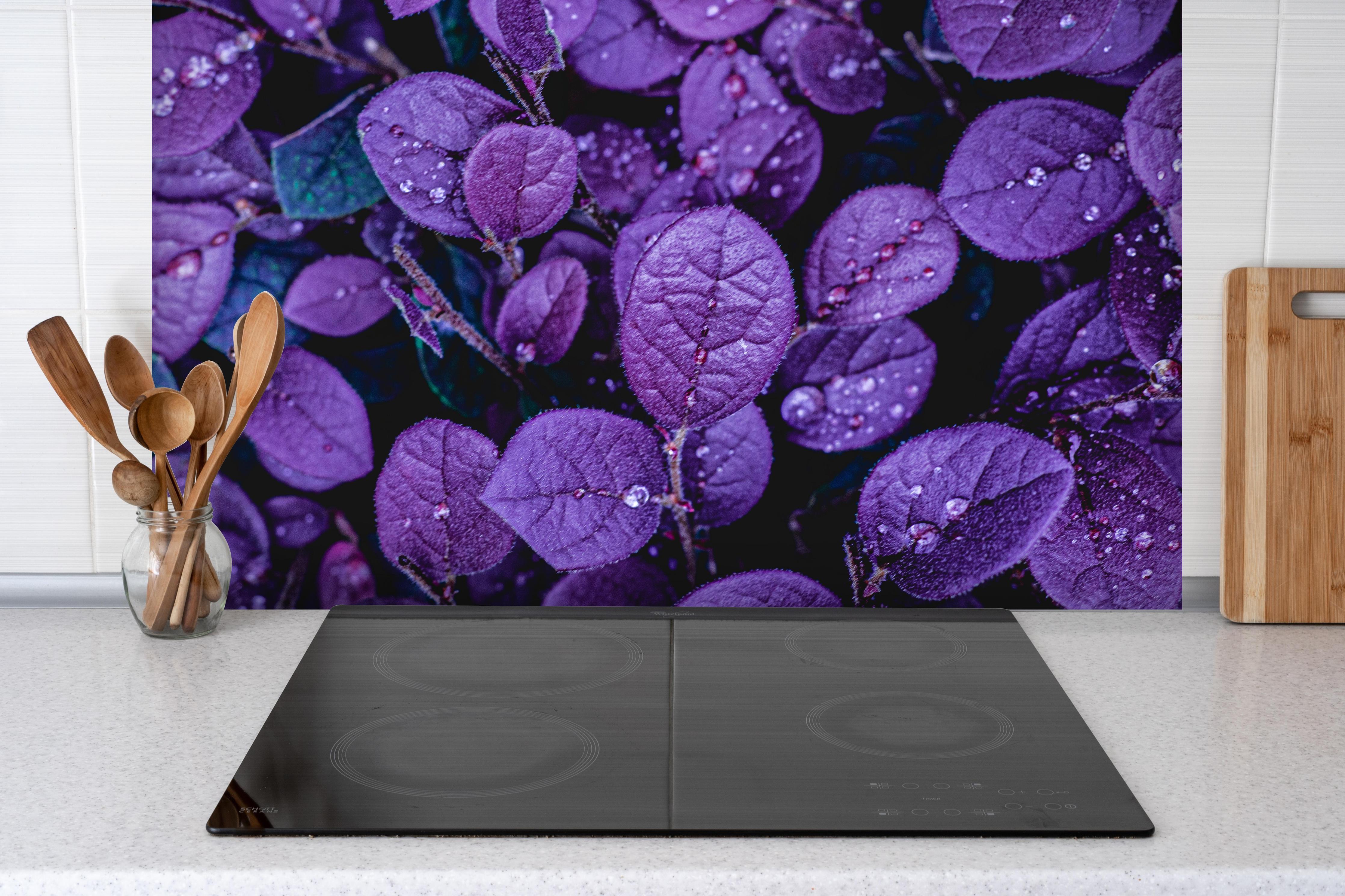 Spritzschutz - Abstrakte Lila Blätter hinter einem Cerankochfeld zwischen Holz-Kochutensilien