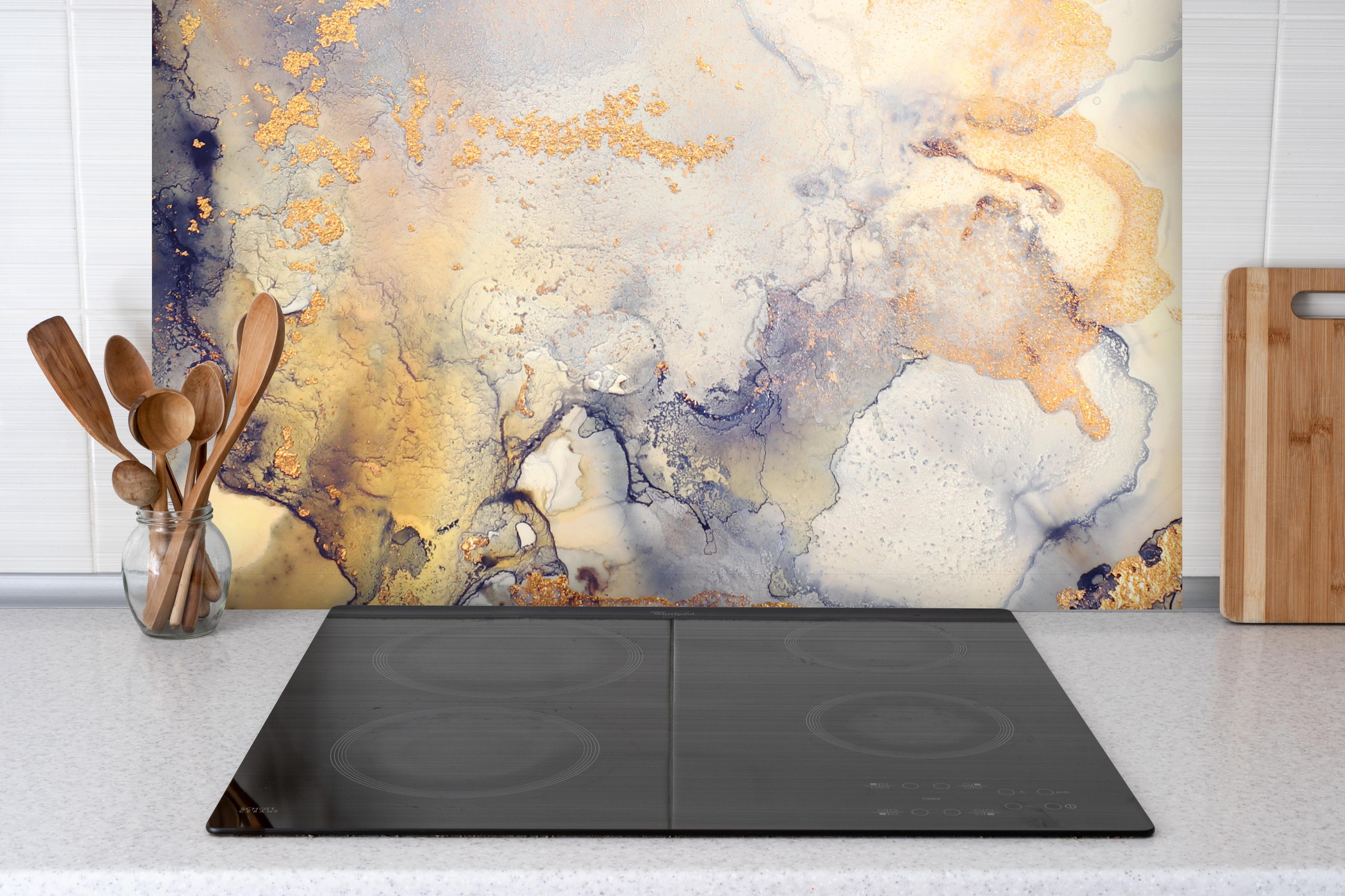 Spritzschutz - Abstrakte goldene Flüssigkunstmalerei hinter einem Cerankochfeld zwischen Holz-Kochutensilien