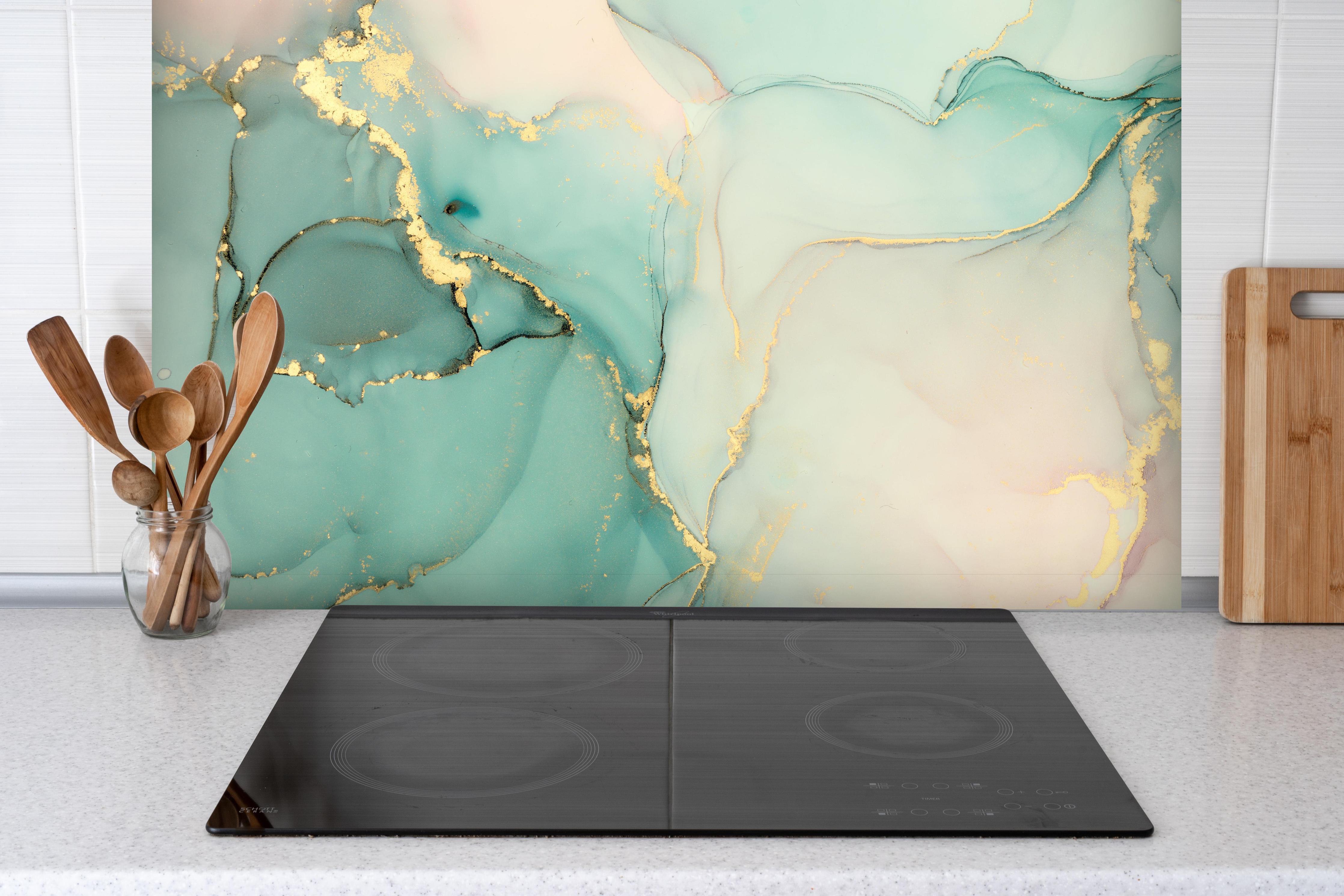 Spritzschutz - Abstrakte grünliche Muster mit goldenem Rand hinter einem Cerankochfeld zwischen Holz-Kochutensilien