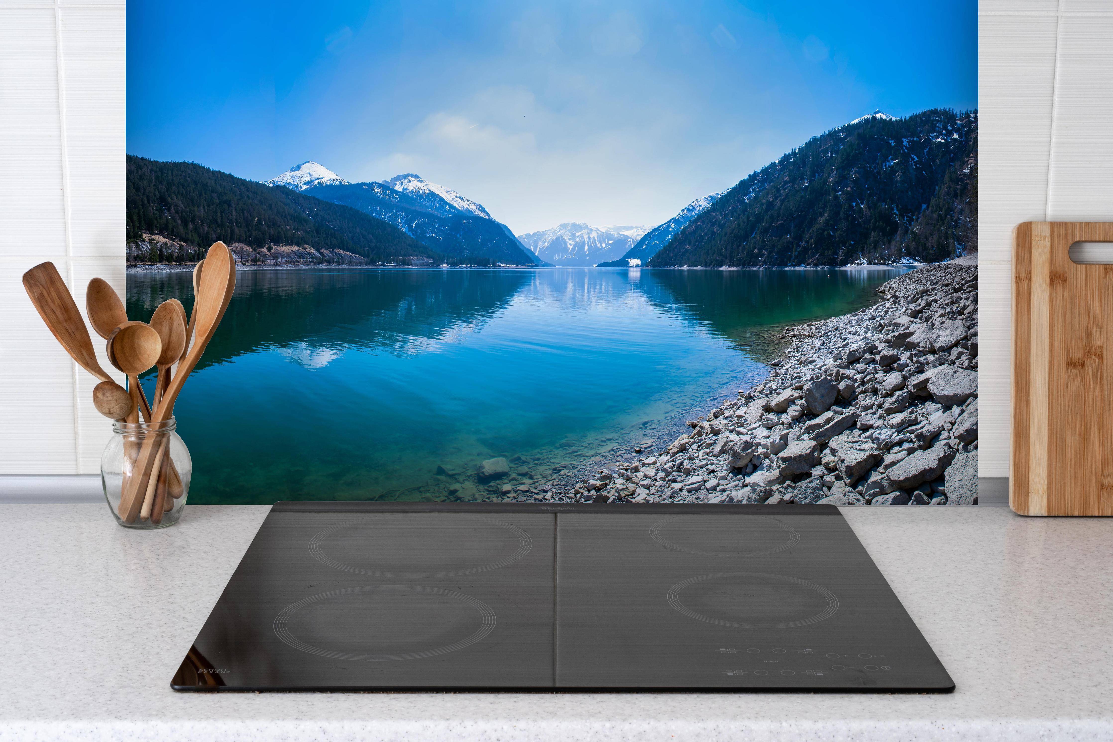 Spritzschutz - Achensee in Österreich hinter einem Cerankochfeld zwischen Holz-Kochutensilien