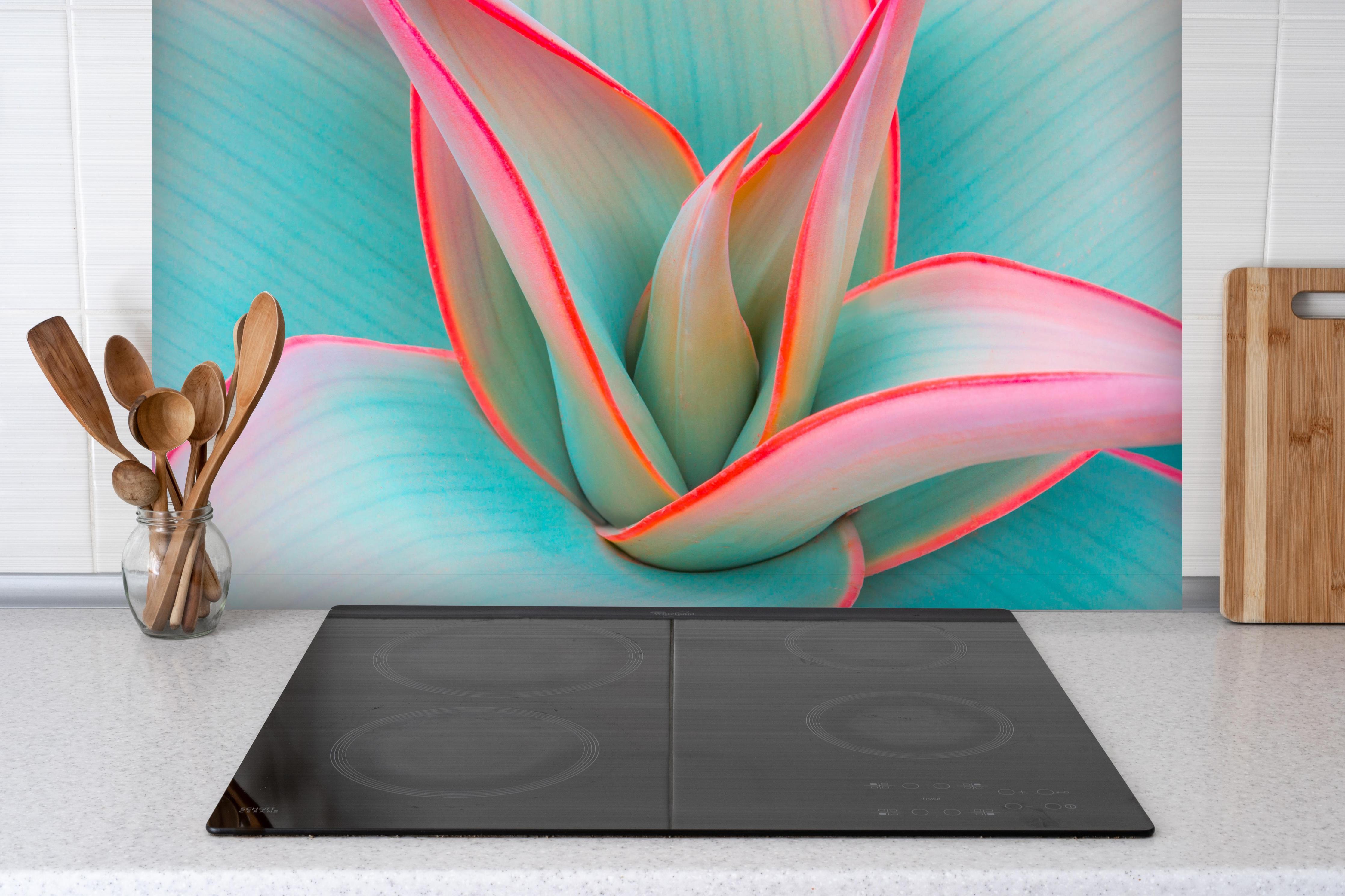 Spritzschutz - Agavenblätter in trendigen Pastellfarben hinter einem Cerankochfeld zwischen Holz-Kochutensilien