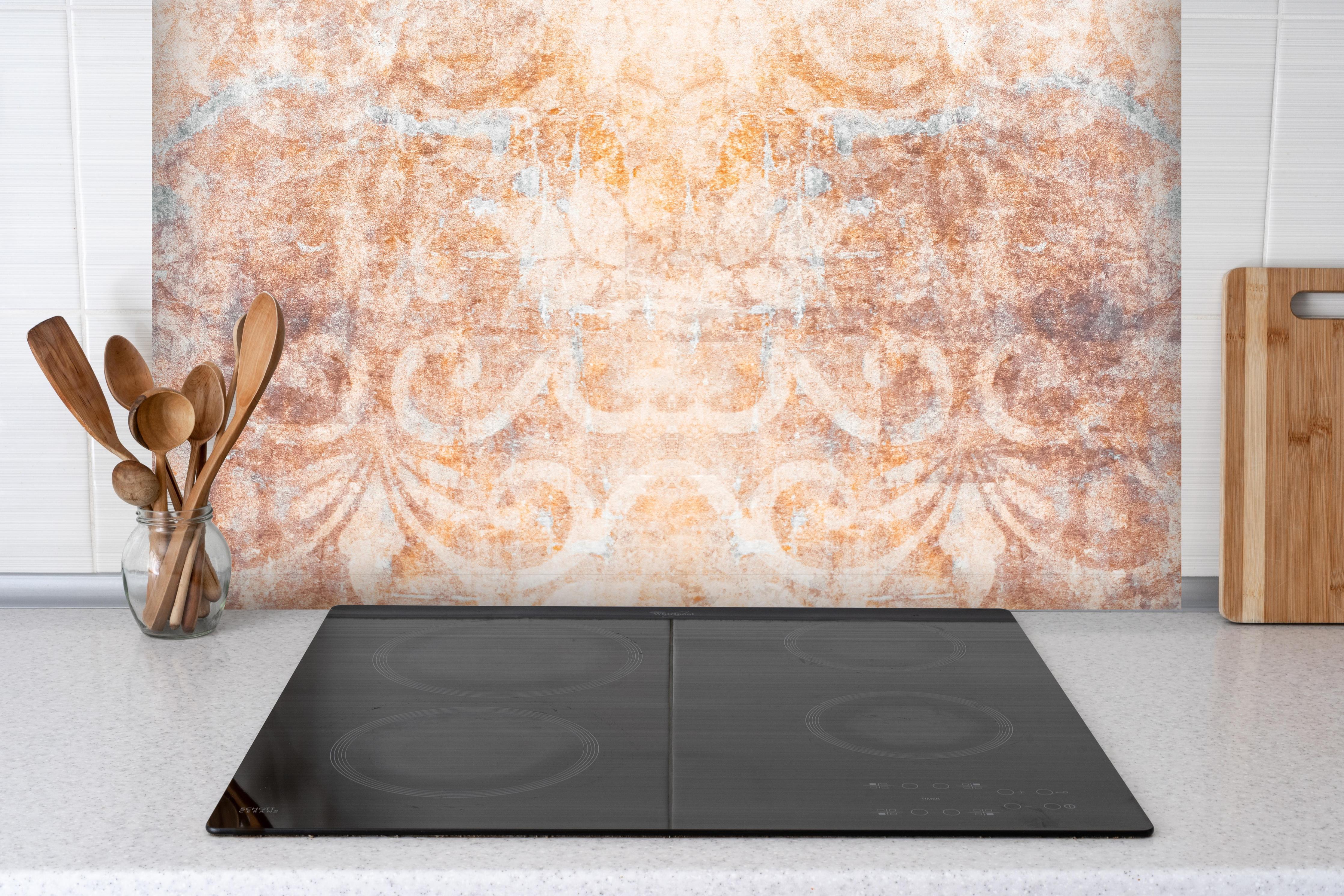 Spritzschutz - Alte braun-orange-weiß Fliesenpatchwork hinter einem Cerankochfeld zwischen Holz-Kochutensilien