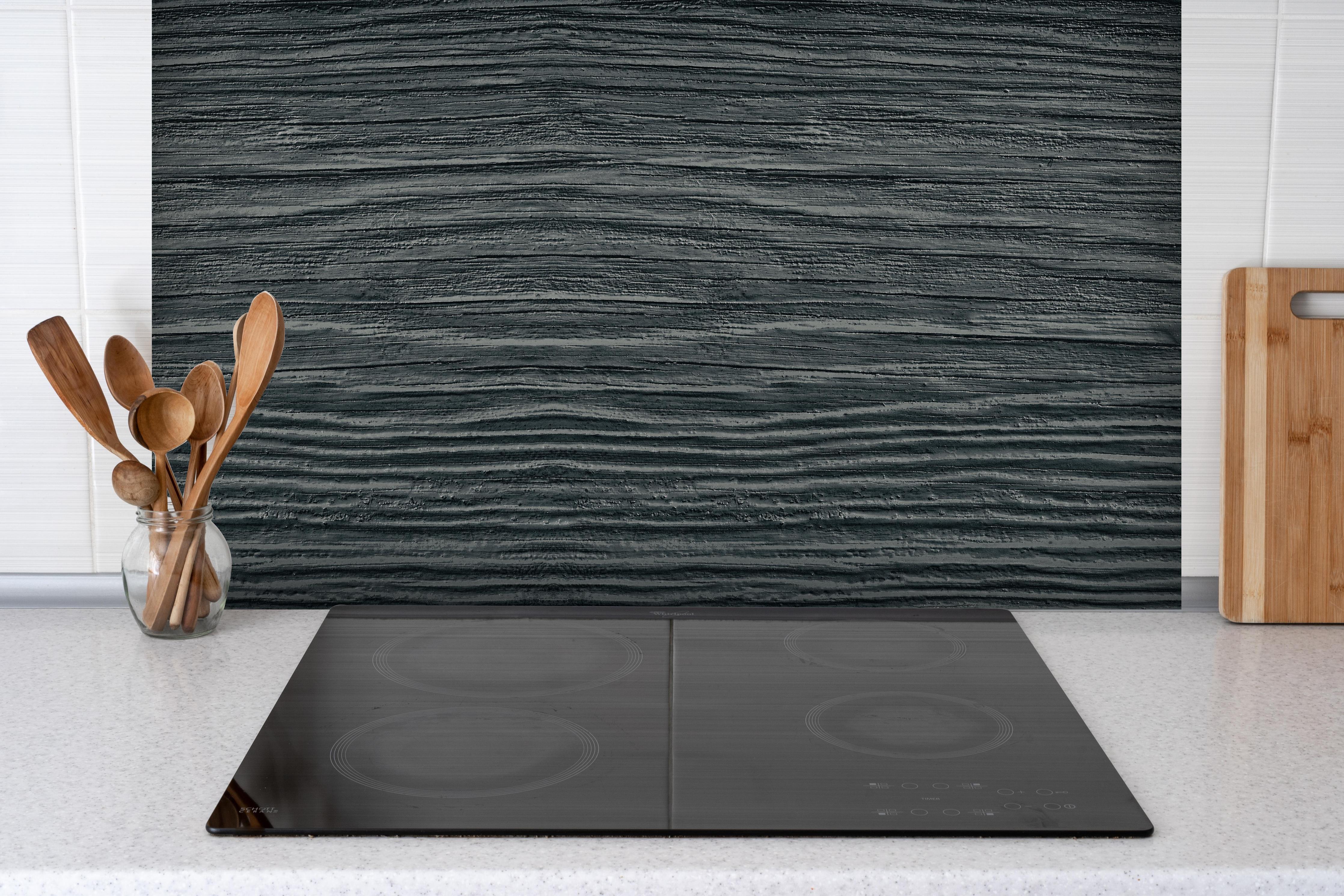 Spritzschutz - Alte geknackte schwarz lackiert Massivholz hinter einem Cerankochfeld zwischen Holz-Kochutensilien