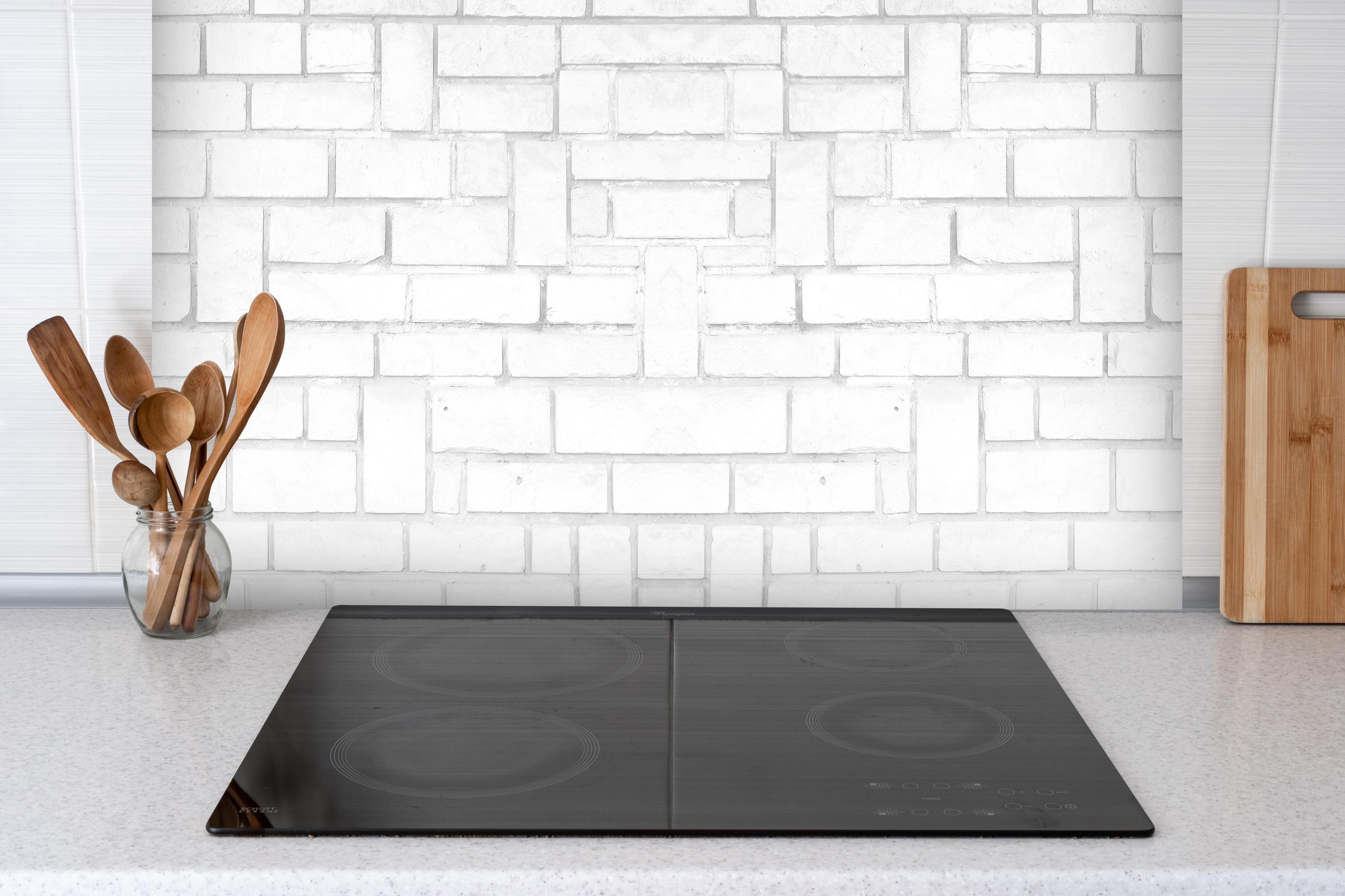 Spritzschutz - Alte weiße Backsteinmauer Muster hinter einem Cerankochfeld zwischen Holz-Kochutensilien