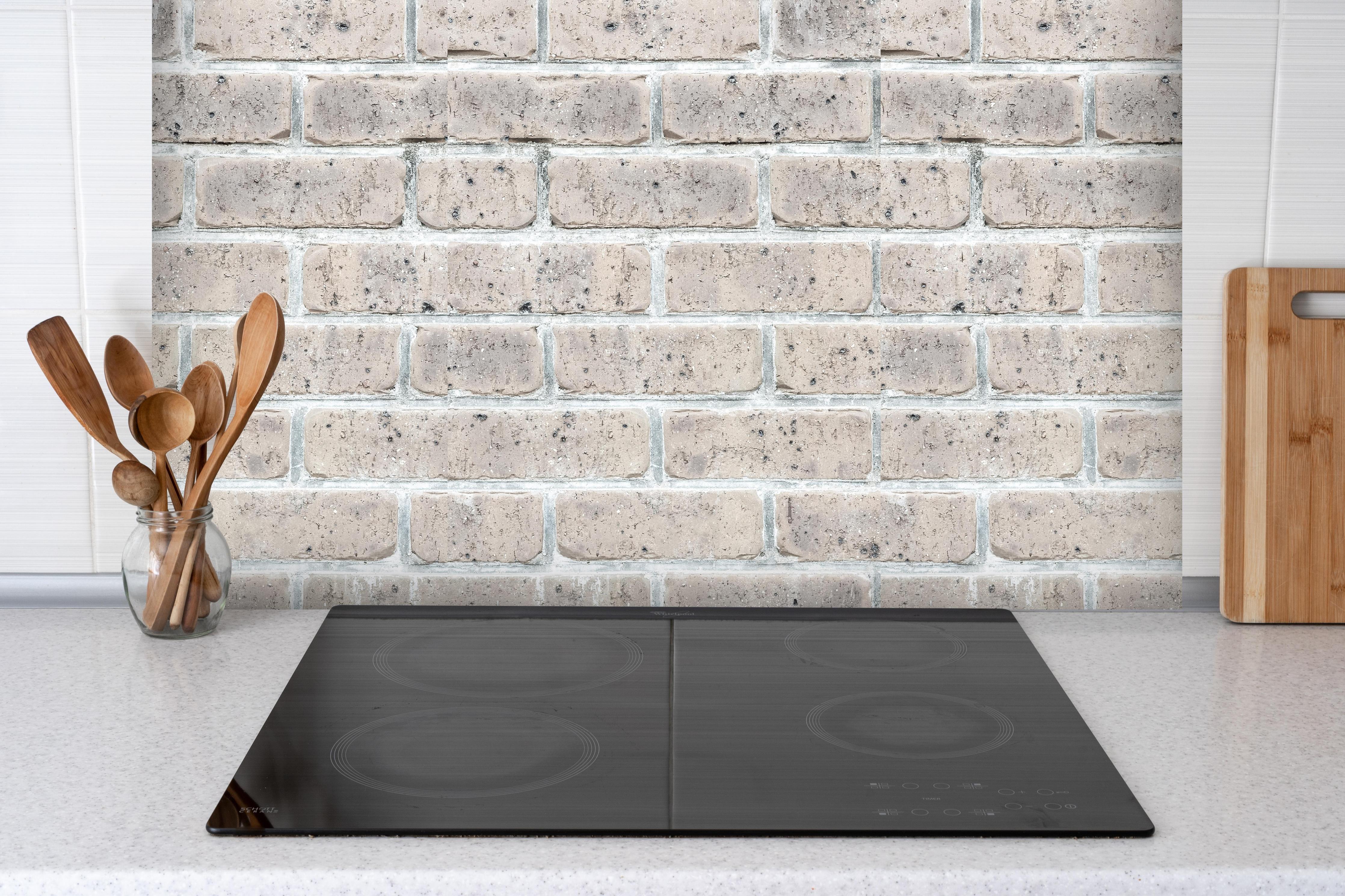 Spritzschutz - Alte weiße Vintage Backsteinmauer hinter einem Cerankochfeld zwischen Holz-Kochutensilien