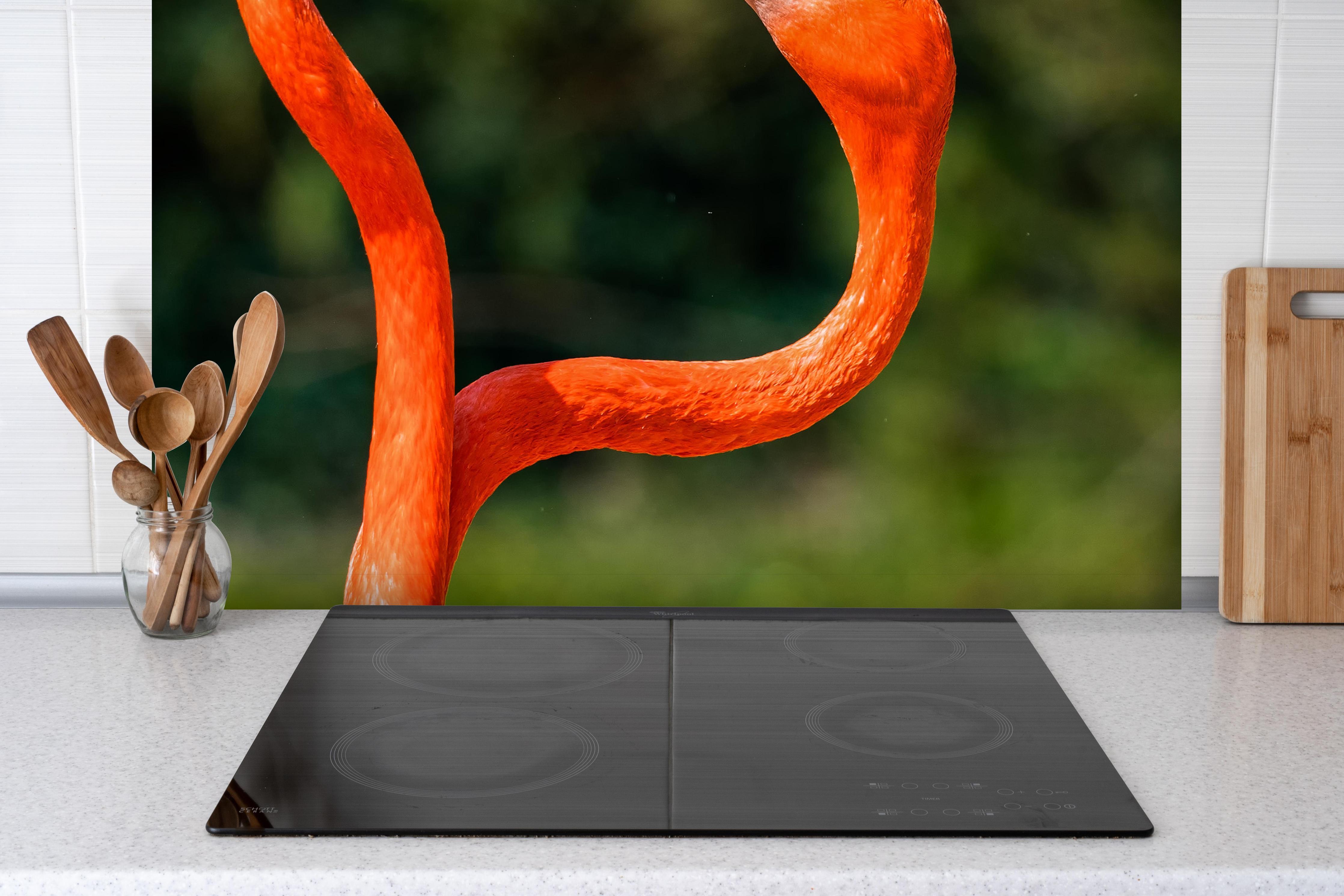 Spritzschutz - Amerikanisches Flamingo-Paar hinter einem Cerankochfeld zwischen Holz-Kochutensilien