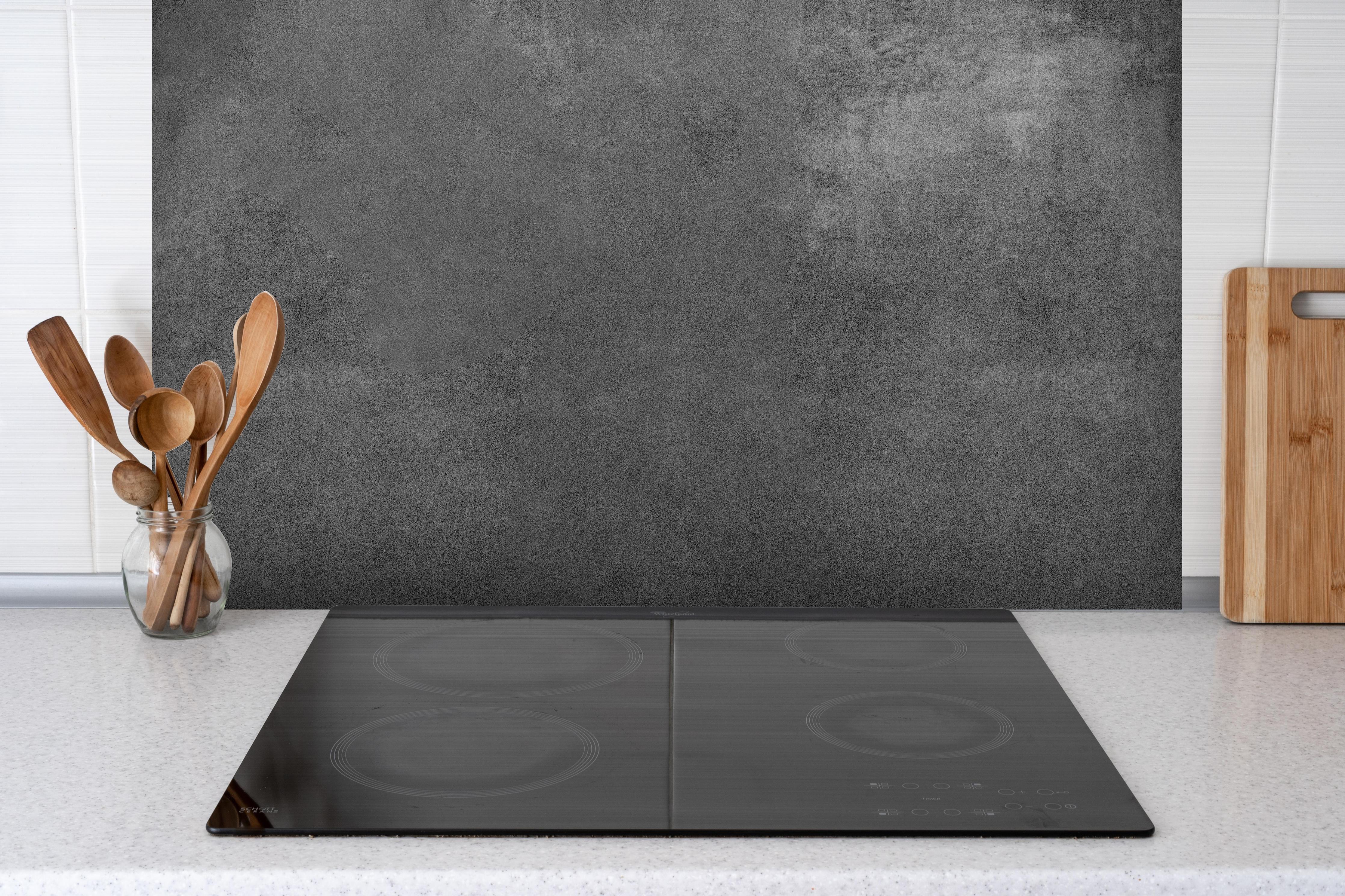 Spritzschutz - Anthrazit Beton Textur hinter einem Cerankochfeld zwischen Holz-Kochutensilien