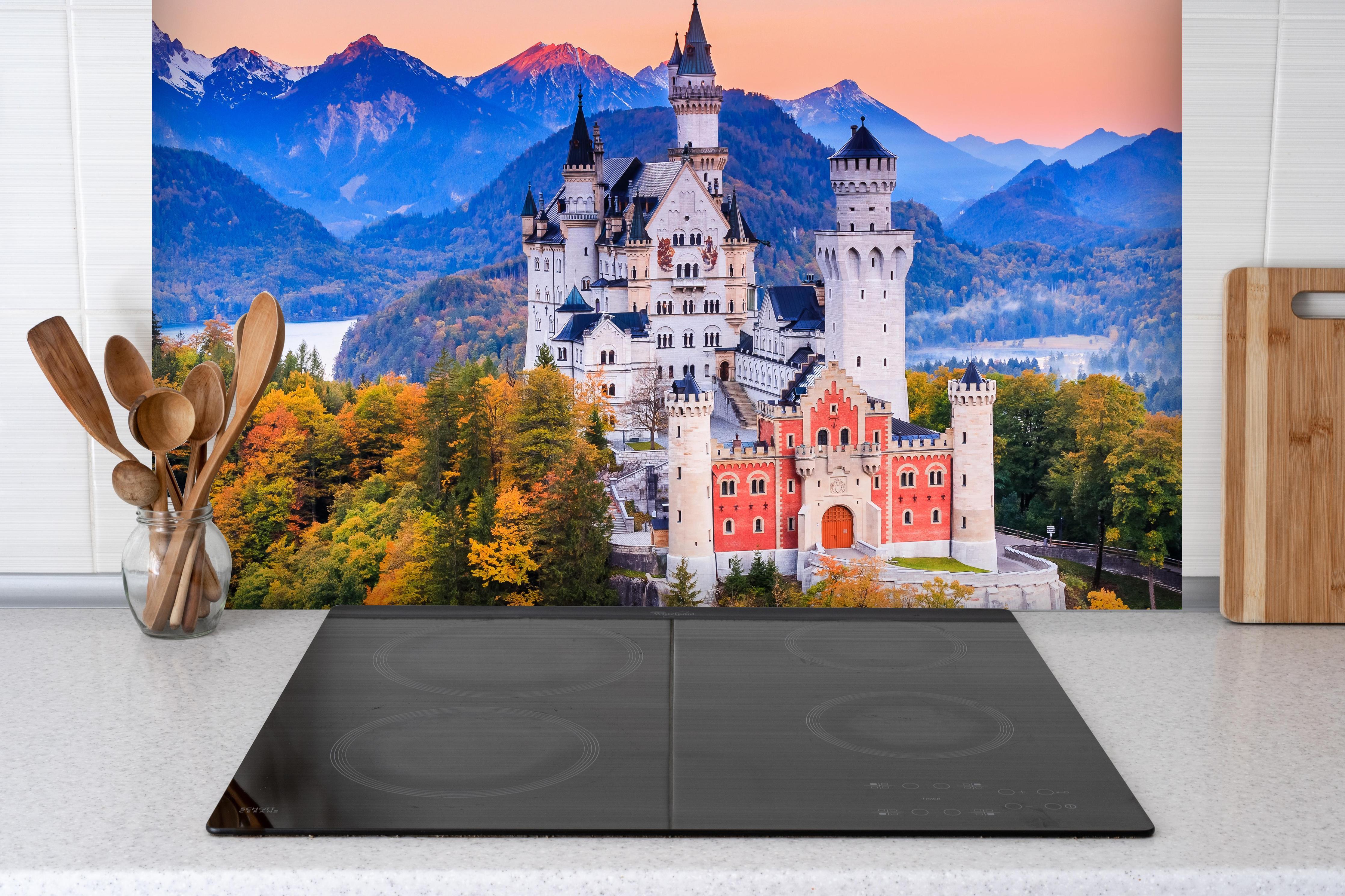 Spritzschutz - Ästhetisches Schloss Neuschawn hinter einem Cerankochfeld zwischen Holz-Kochutensilien