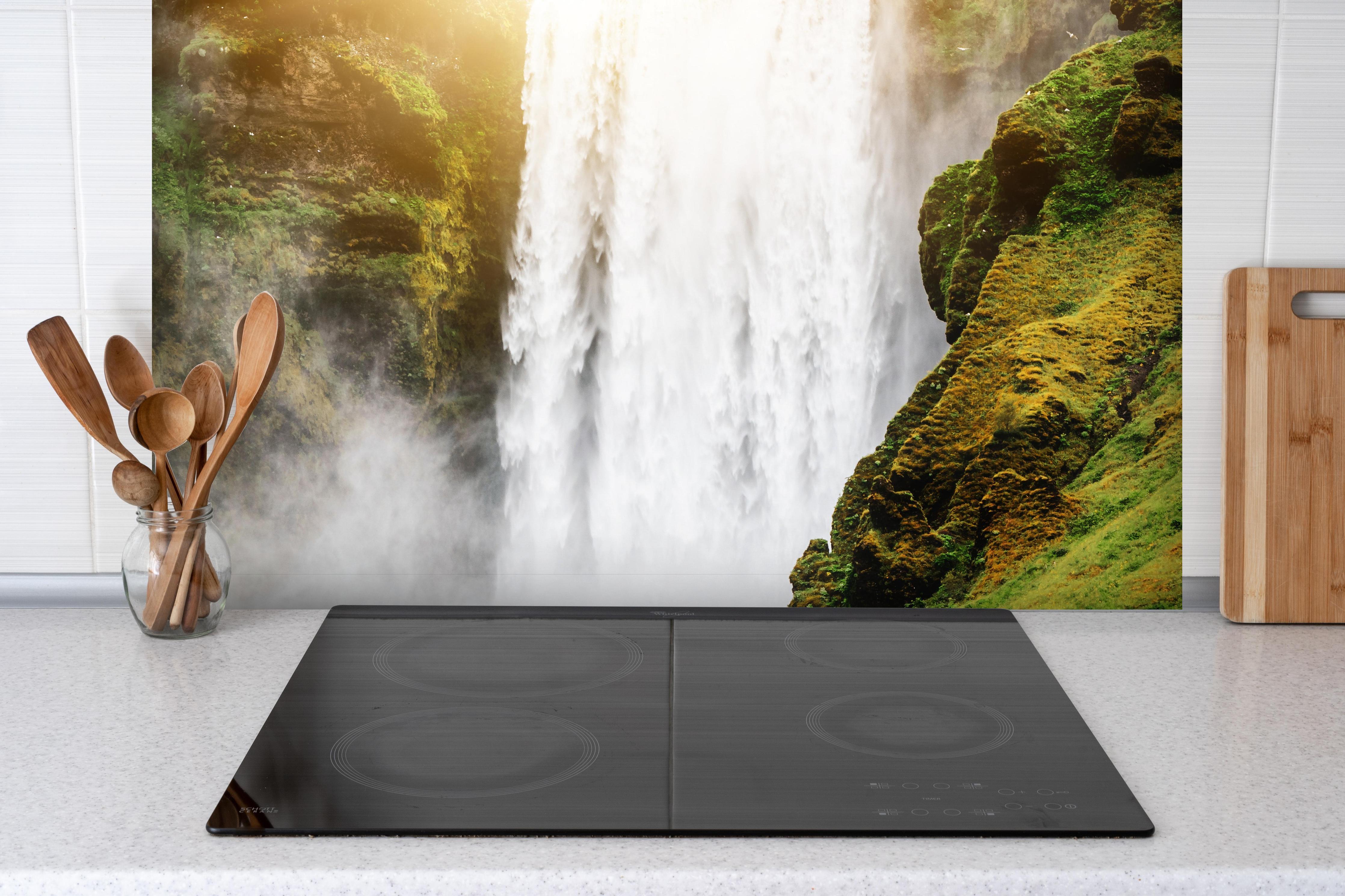 Spritzschutz - Atemberaubender Wasserfall in Island hinter einem Cerankochfeld zwischen Holz-Kochutensilien