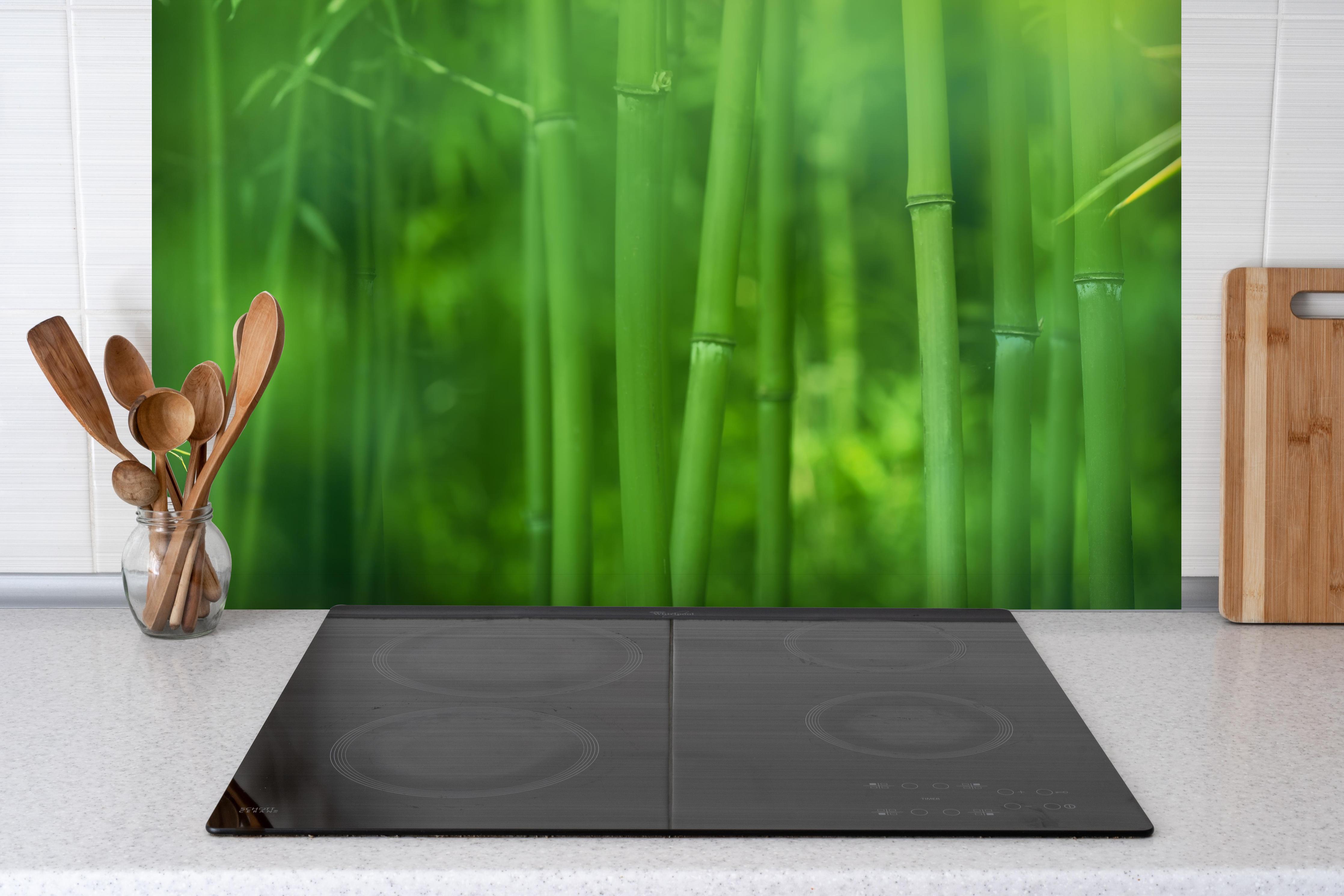 Spritzschutz - Bambuswald hinter einem Cerankochfeld zwischen Holz-Kochutensilien