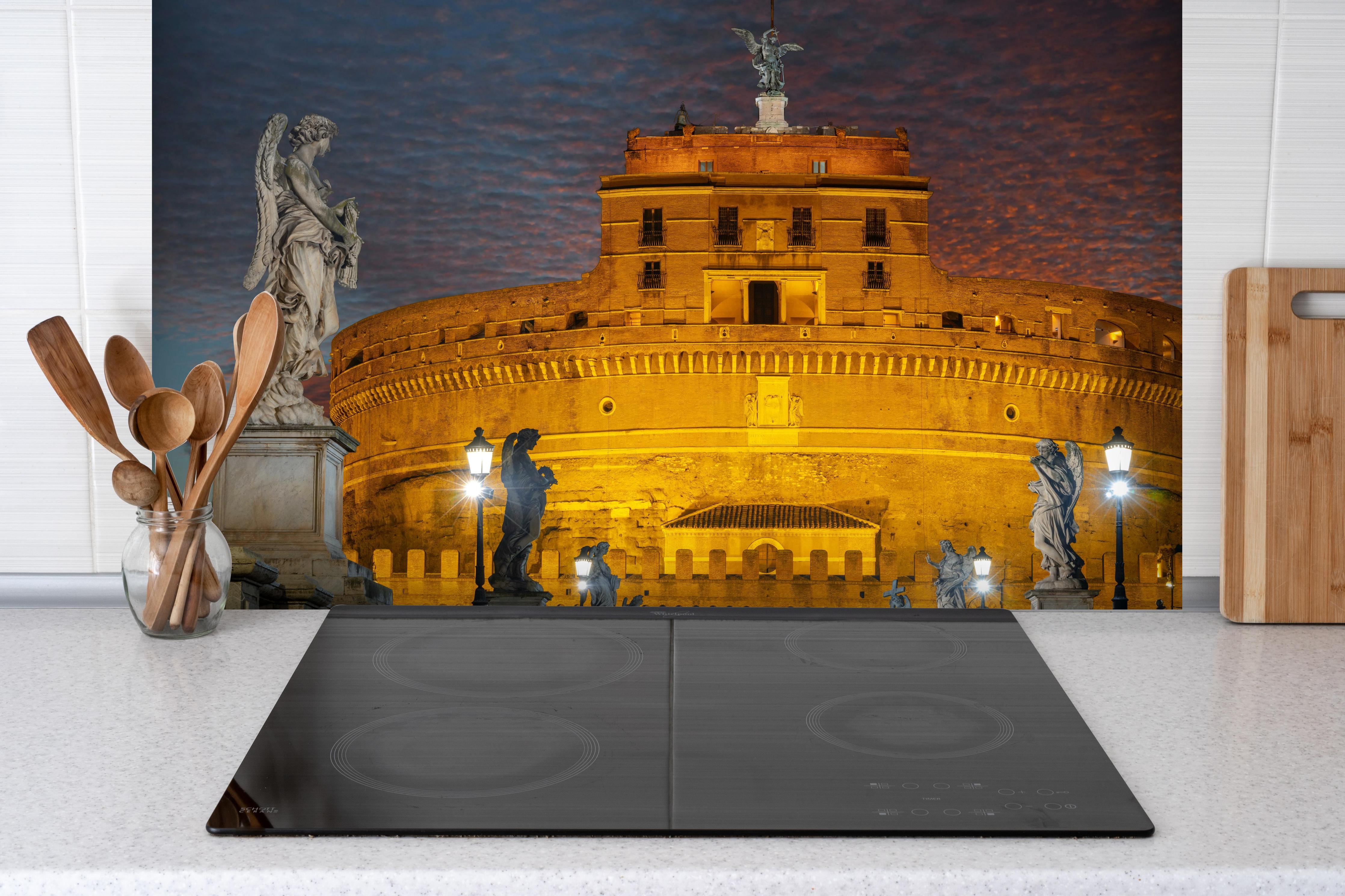 Spritzschutz - Beleuchtete Engelsburg in Rom hinter einem Cerankochfeld zwischen Holz-Kochutensilien