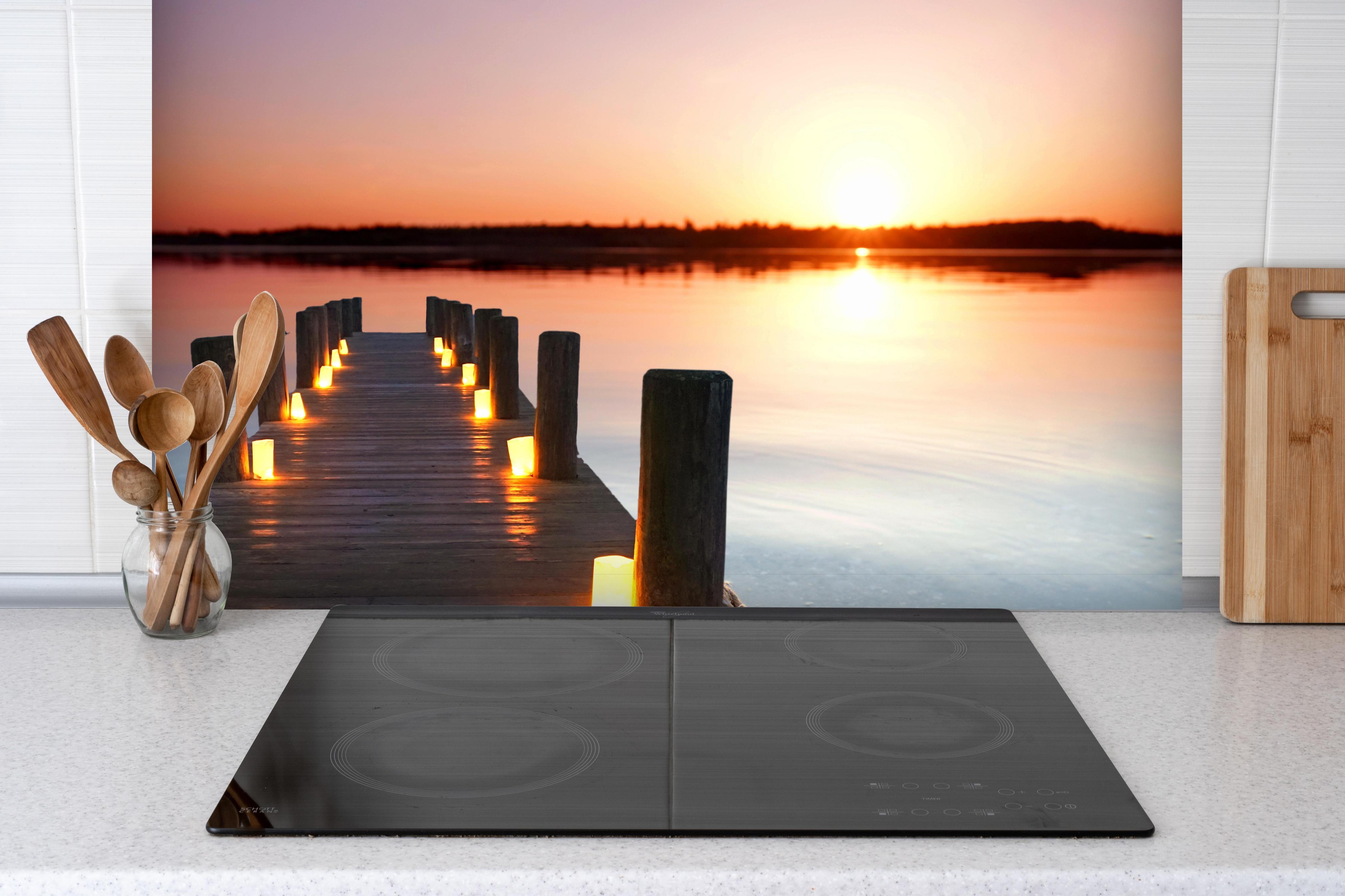 Spritzschutz - Beleuchteter romantischer Steg am Strand hinter einem Cerankochfeld zwischen Holz-Kochutensilien