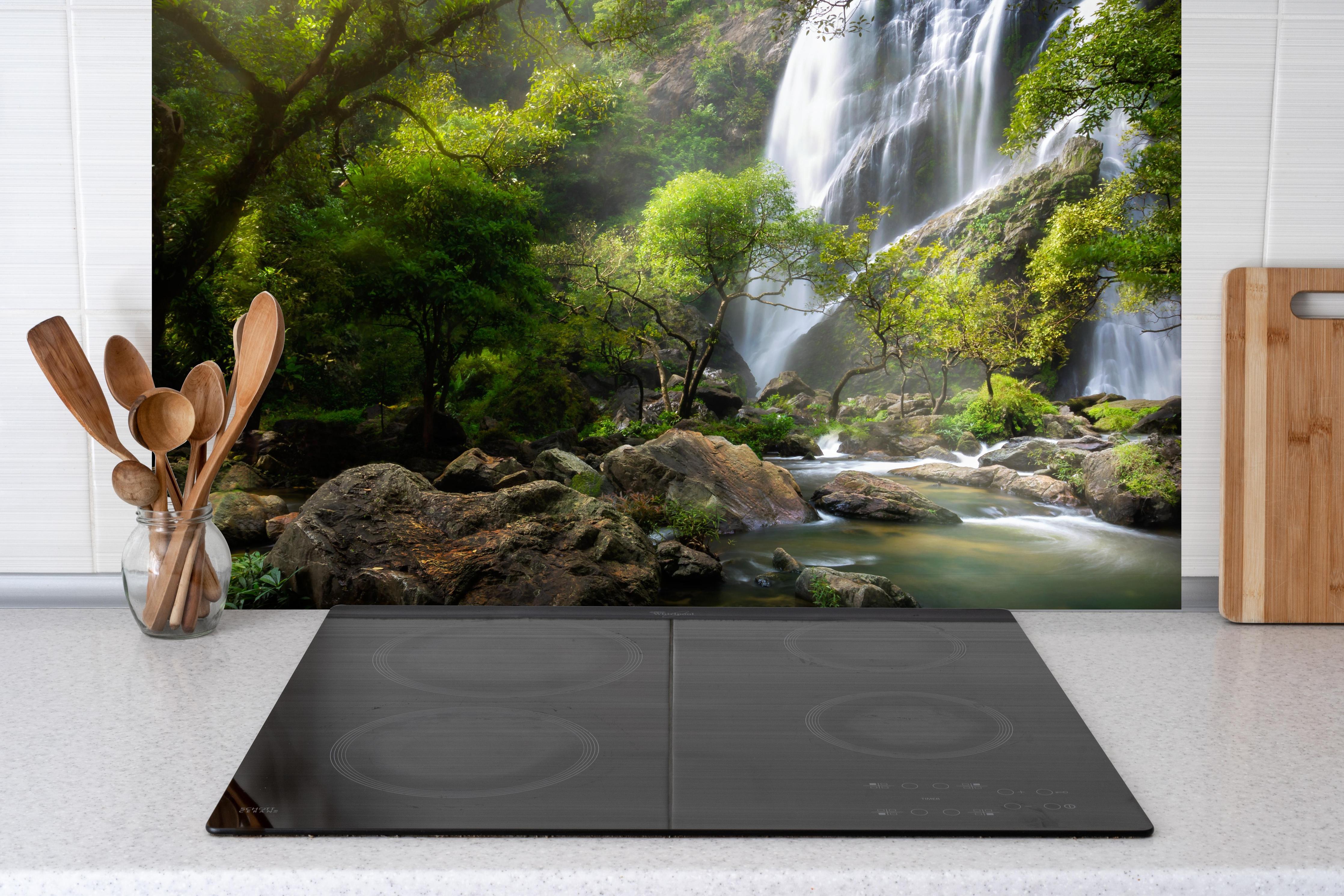 Spritzschutz - Bergbach und Wasserfall in Thailand hinter einem Cerankochfeld zwischen Holz-Kochutensilien