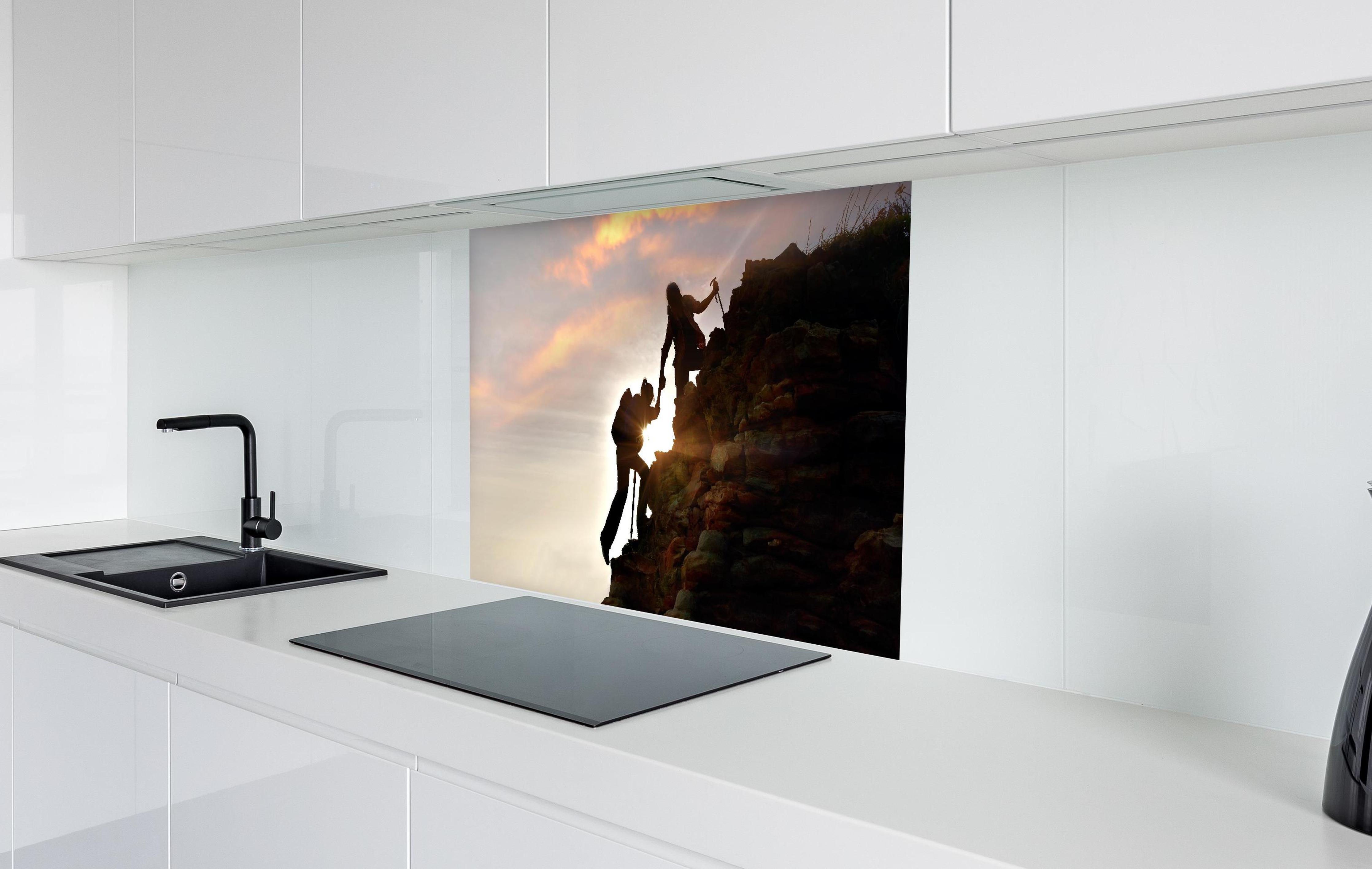Spritzschutz - Bergsteiger bei Sonnenuntergang in weißer Hochglanz-Küche hinter einem Cerankochfeld