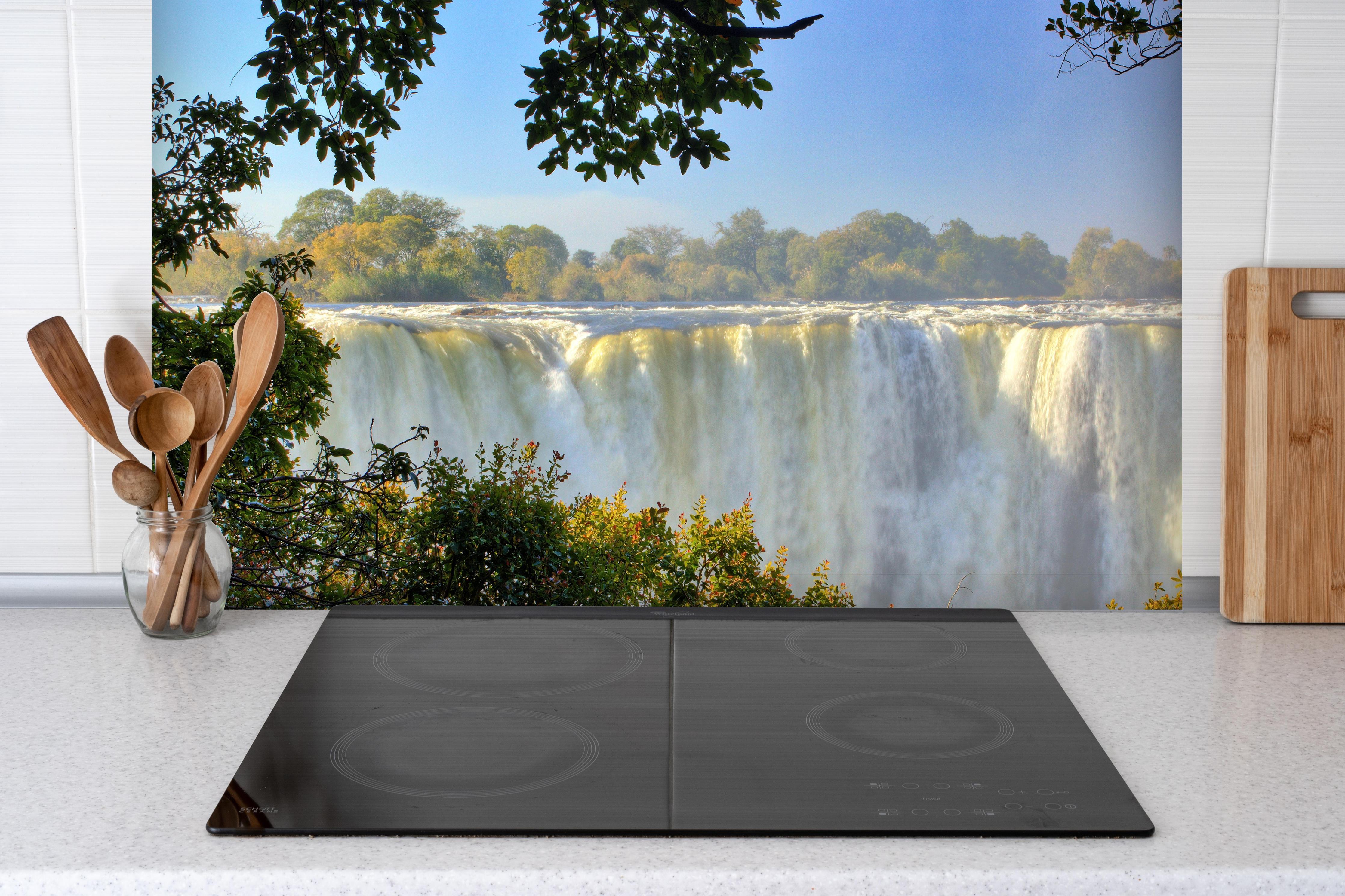 Spritzschutz - Besondere Perspektive auf Victoria Falls hinter einem Cerankochfeld zwischen Holz-Kochutensilien