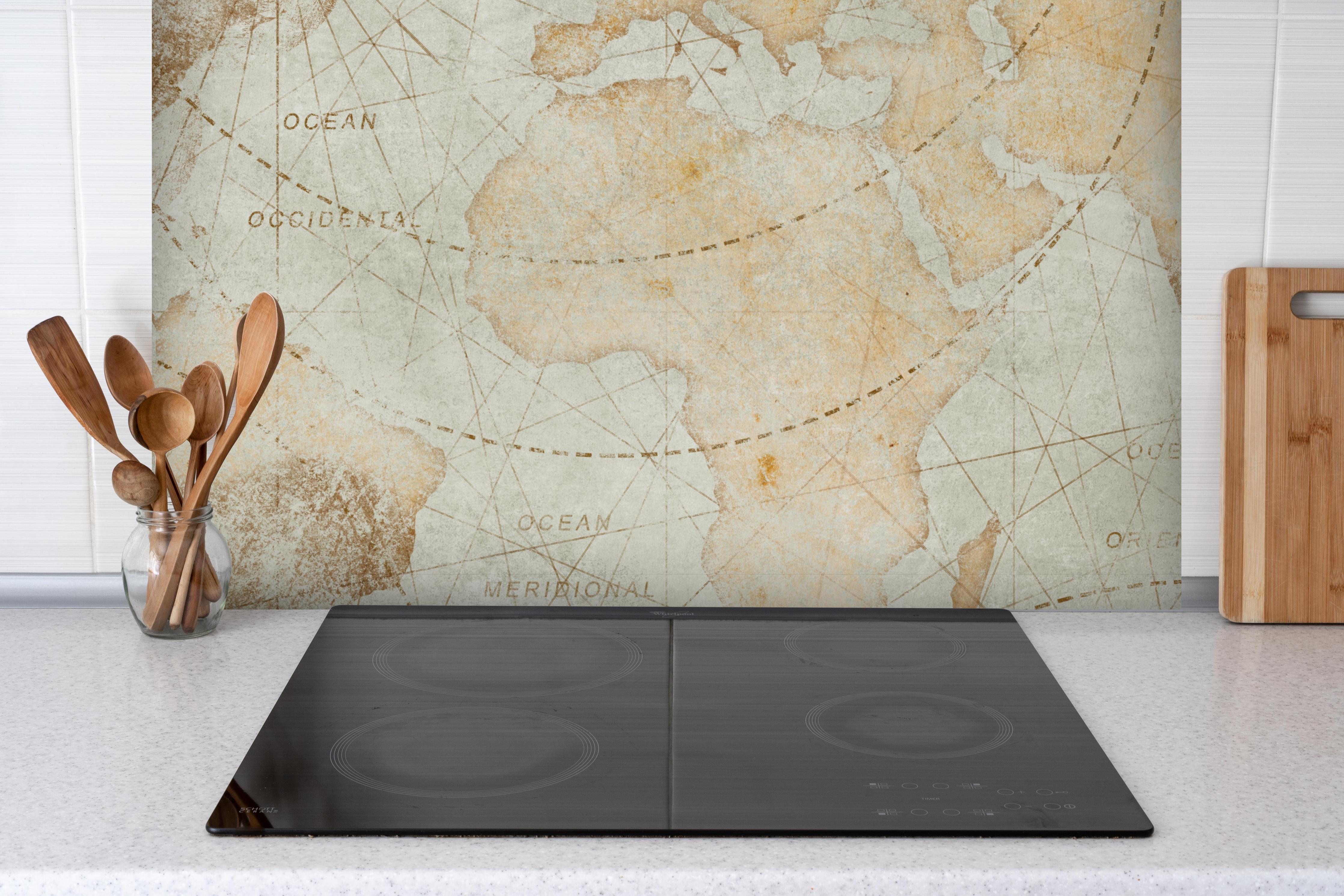 Spritzschutz - Bläuliche Vintage-Weltkarte hinter einem Cerankochfeld zwischen Holz-Kochutensilien