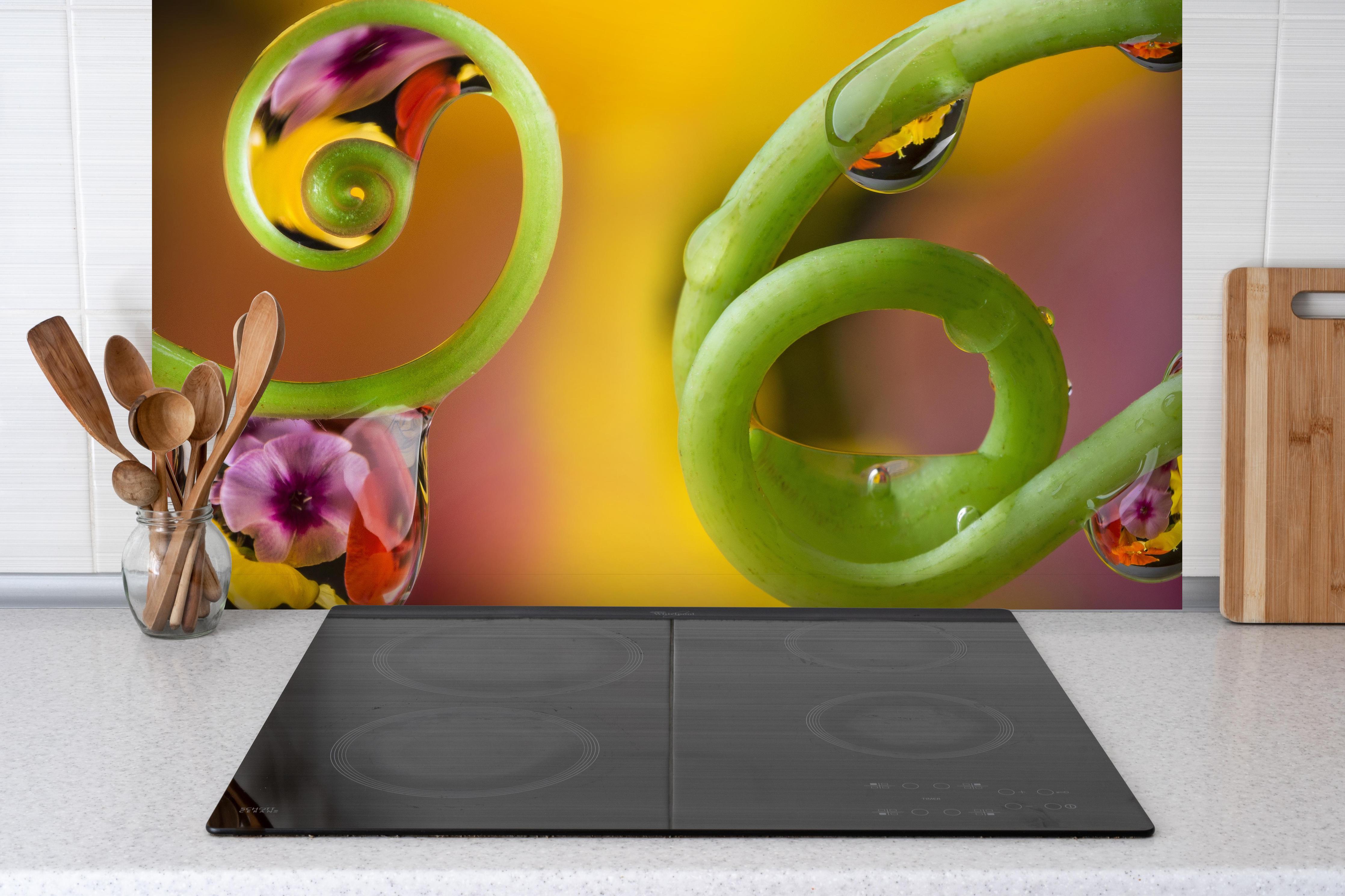 Spritzschutz - Blume mit abstrakten Tropfen hinter einem Cerankochfeld zwischen Holz-Kochutensilien