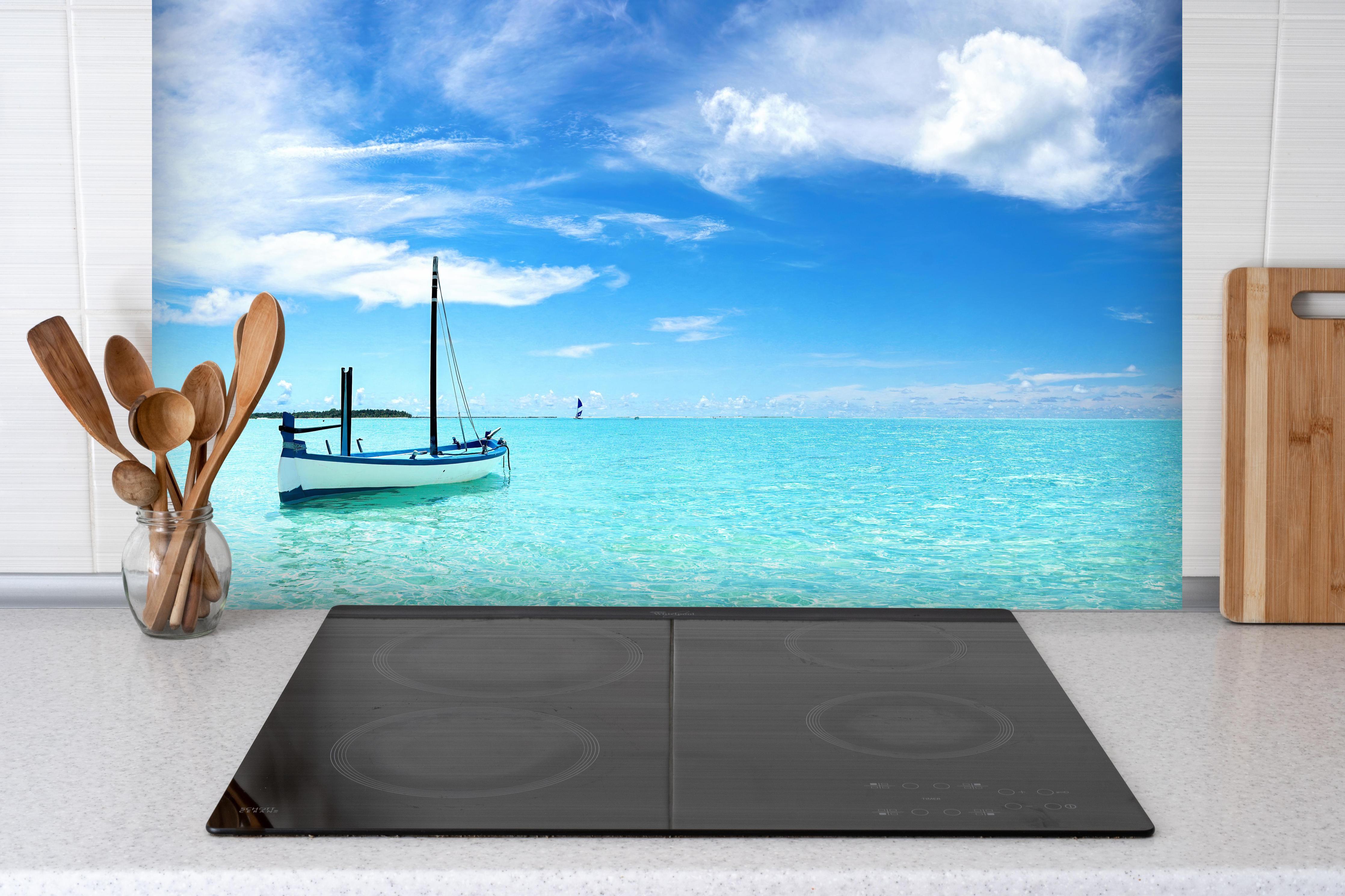 Spritzschutz - Boot im türkisfarbenen Meerwasser hinter einem Cerankochfeld zwischen Holz-Kochutensilien