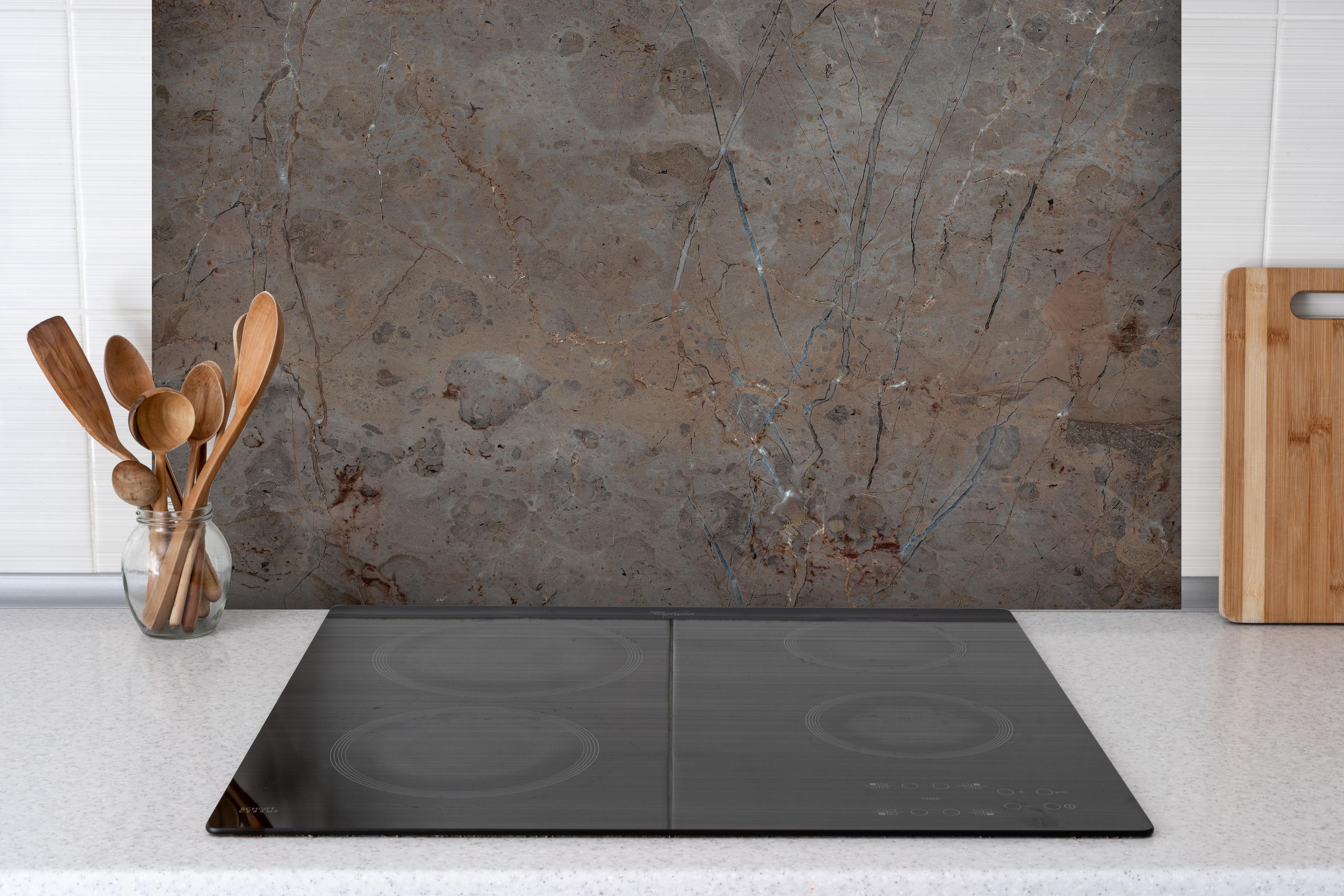 Spritzschutz - Bräunliche Marmortextur hinter einem Cerankochfeld zwischen Holz-Kochutensilien