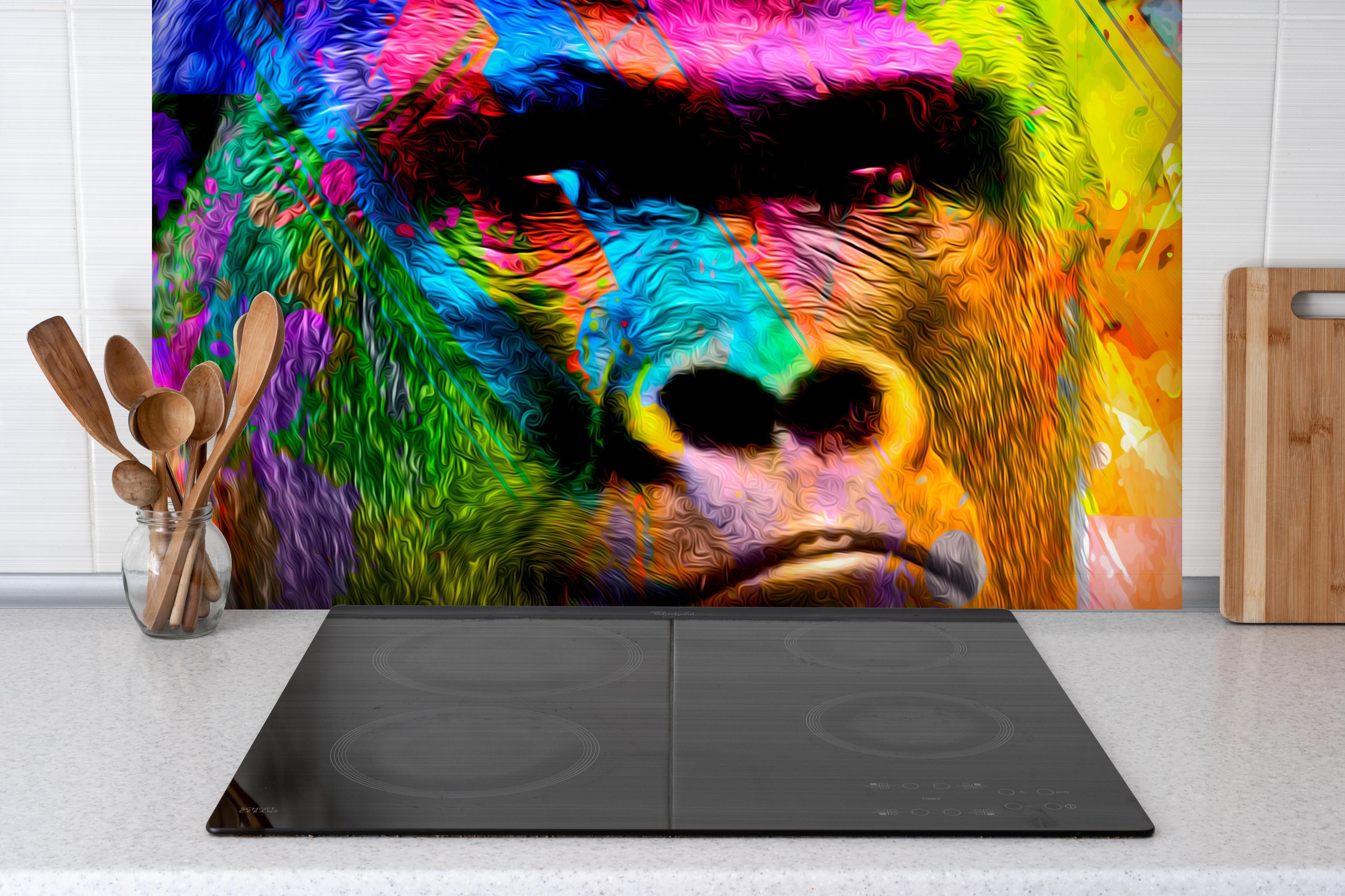 Spritzschutz - Bunter abstrakter Gorillakopf hinter einem Cerankochfeld zwischen Holz-Kochutensilien
