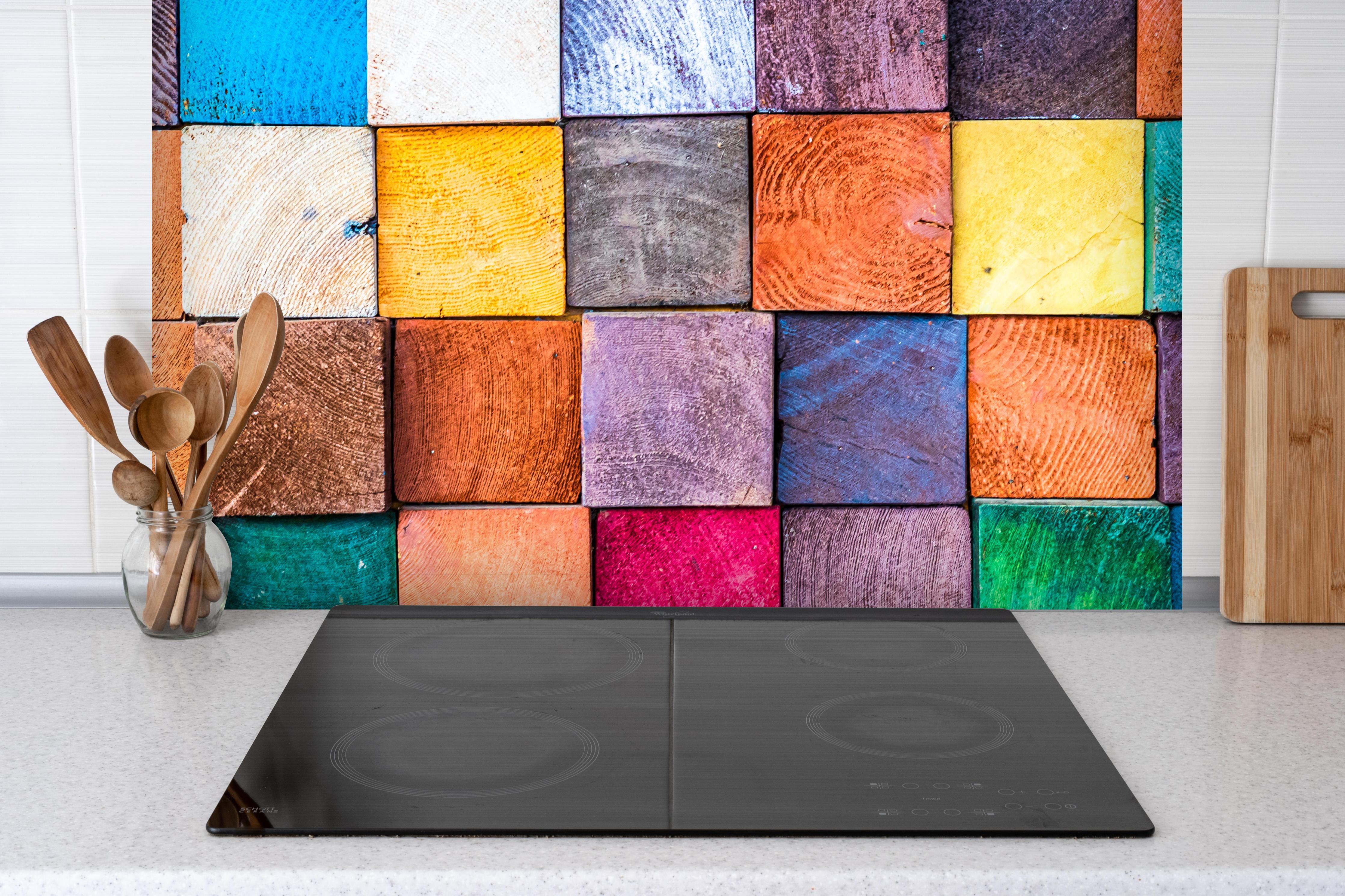 Spritzschutz - Buntes Holzstapelmuster hinter einem Cerankochfeld zwischen Holz-Kochutensilien