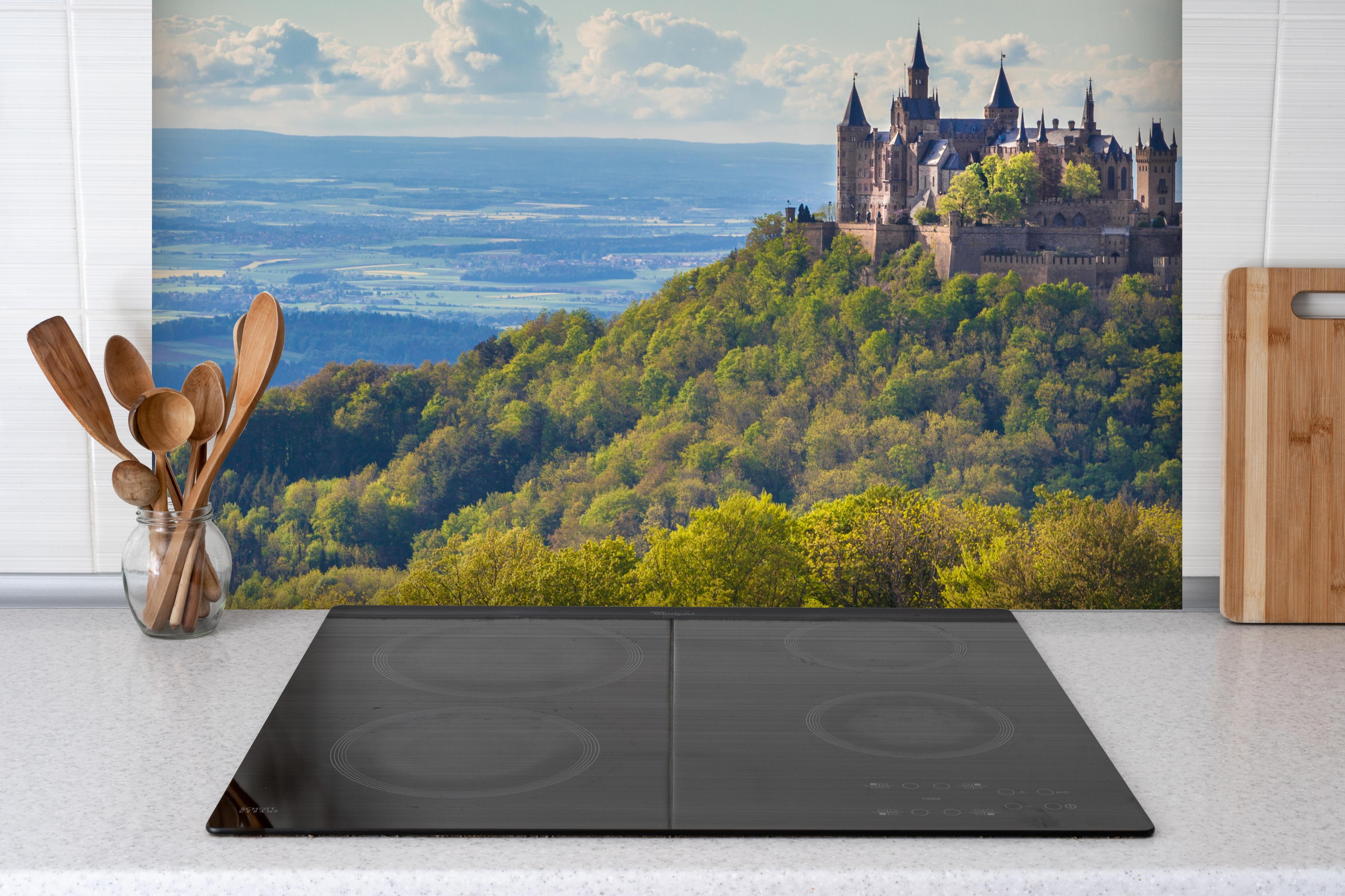 Spritzschutz - Burg Hohenzollern mit gelblichen Wald hinter einem Cerankochfeld zwischen Holz-Kochutensilien