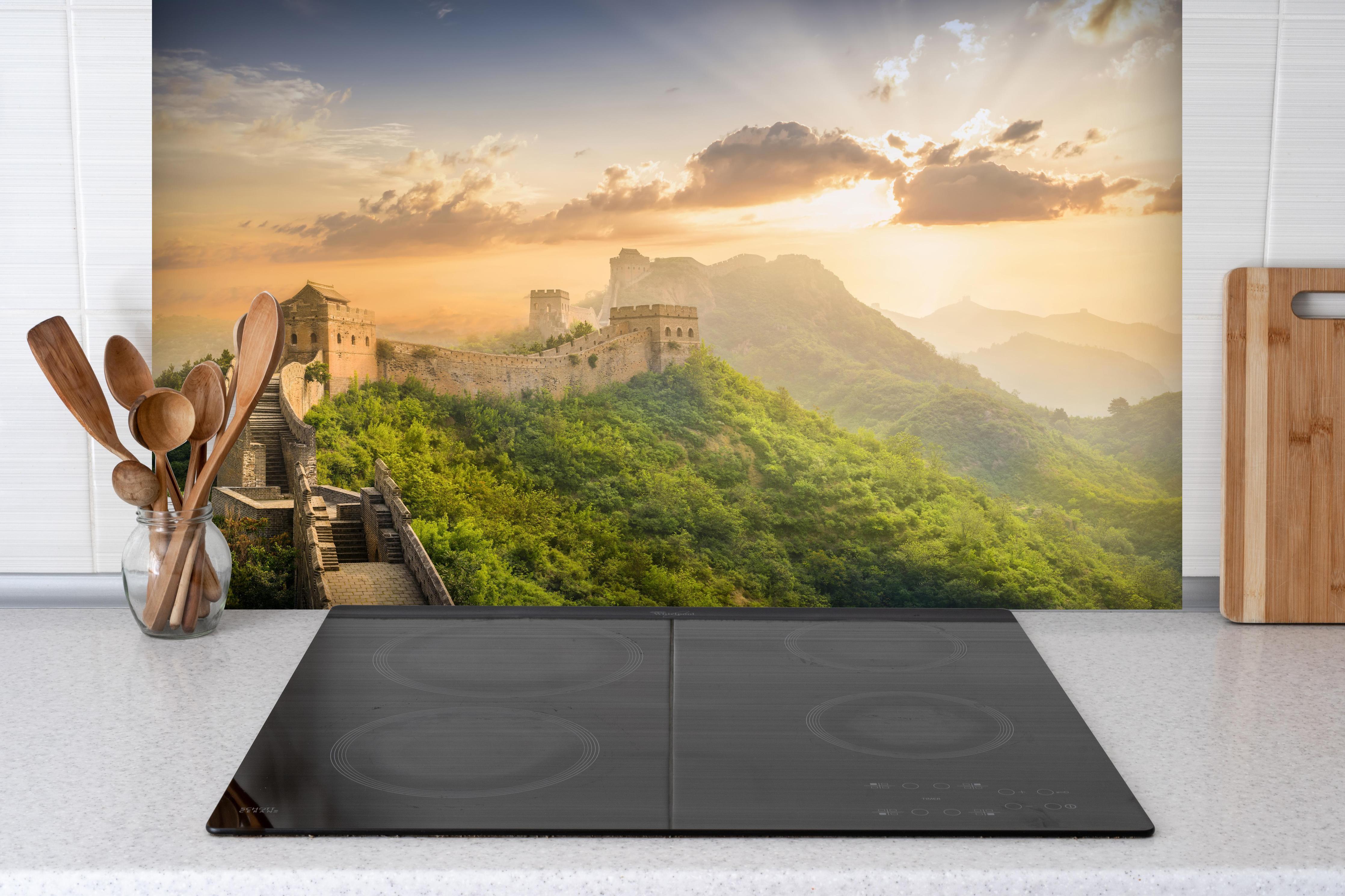 Spritzschutz - Chinesische Mauer bei Sonnenaufgang hinter einem Cerankochfeld zwischen Holz-Kochutensilien