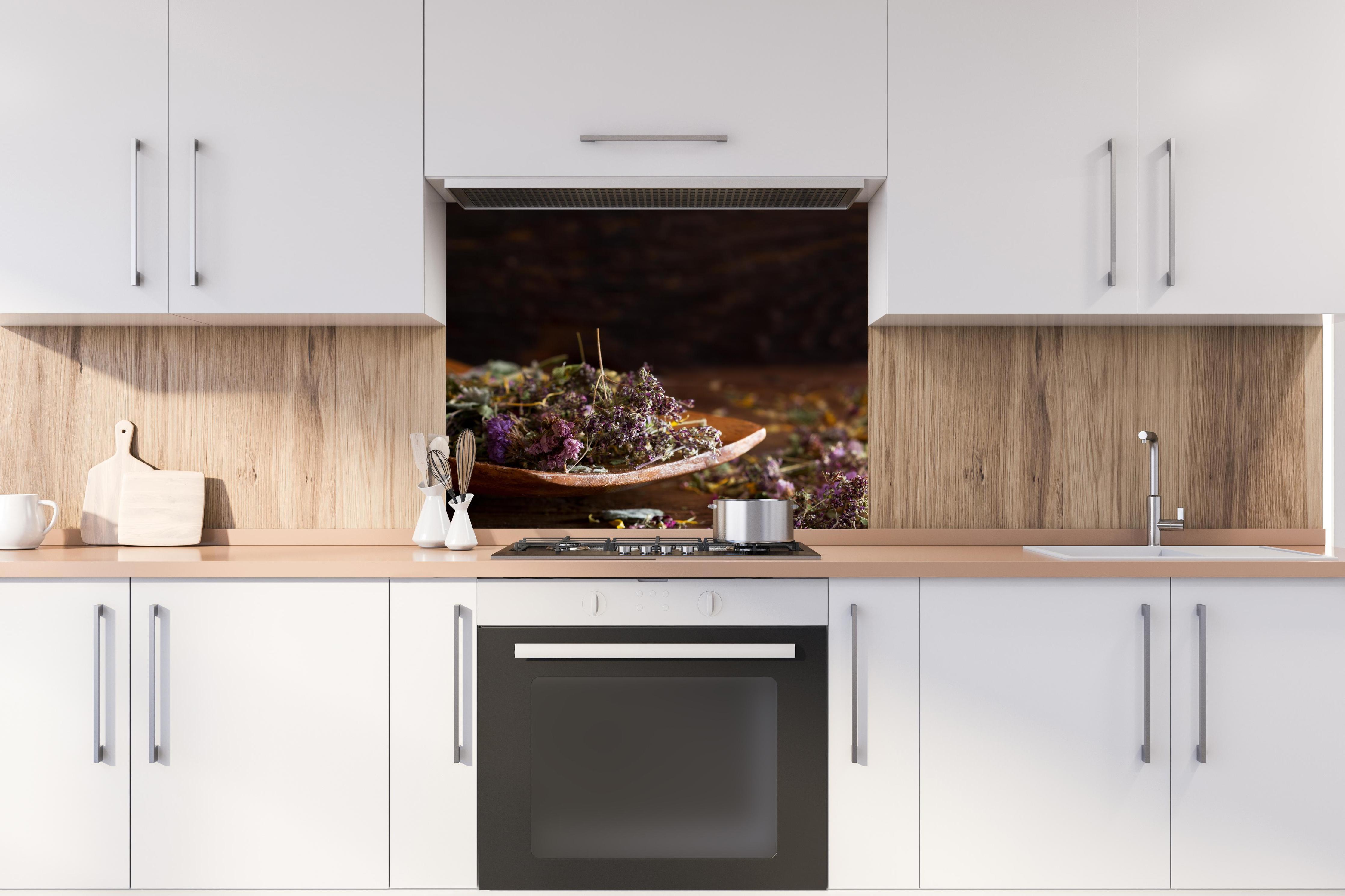 Spritzschutz - Dampfende Tasse Tee mit Kräutern hinter stilvollem Gasherd unter Dunstabzugshaube