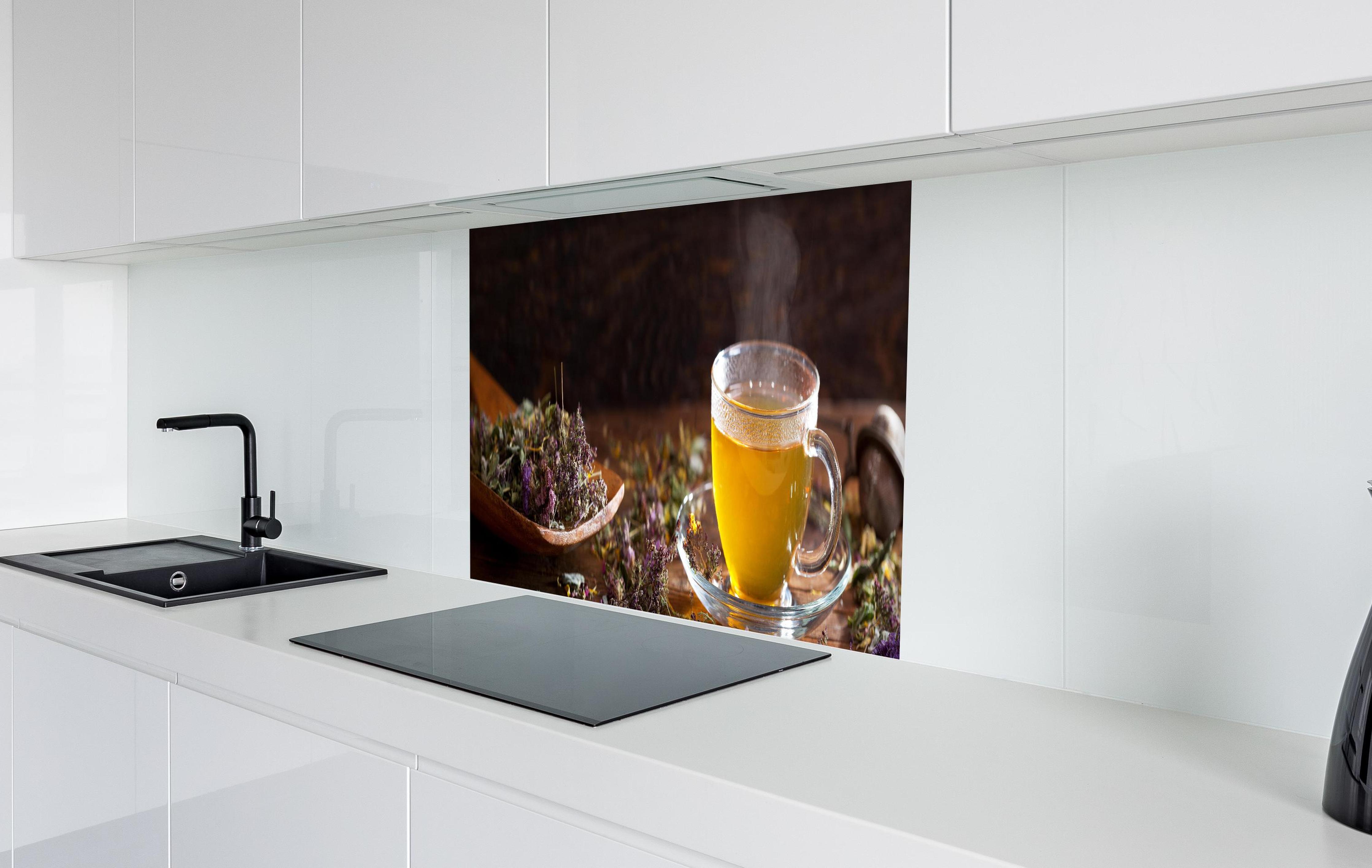 Spritzschutz - Dampfende Tasse Tee mit Kräutern in weißer Hochglanz-Küche hinter einem Cerankochfeld