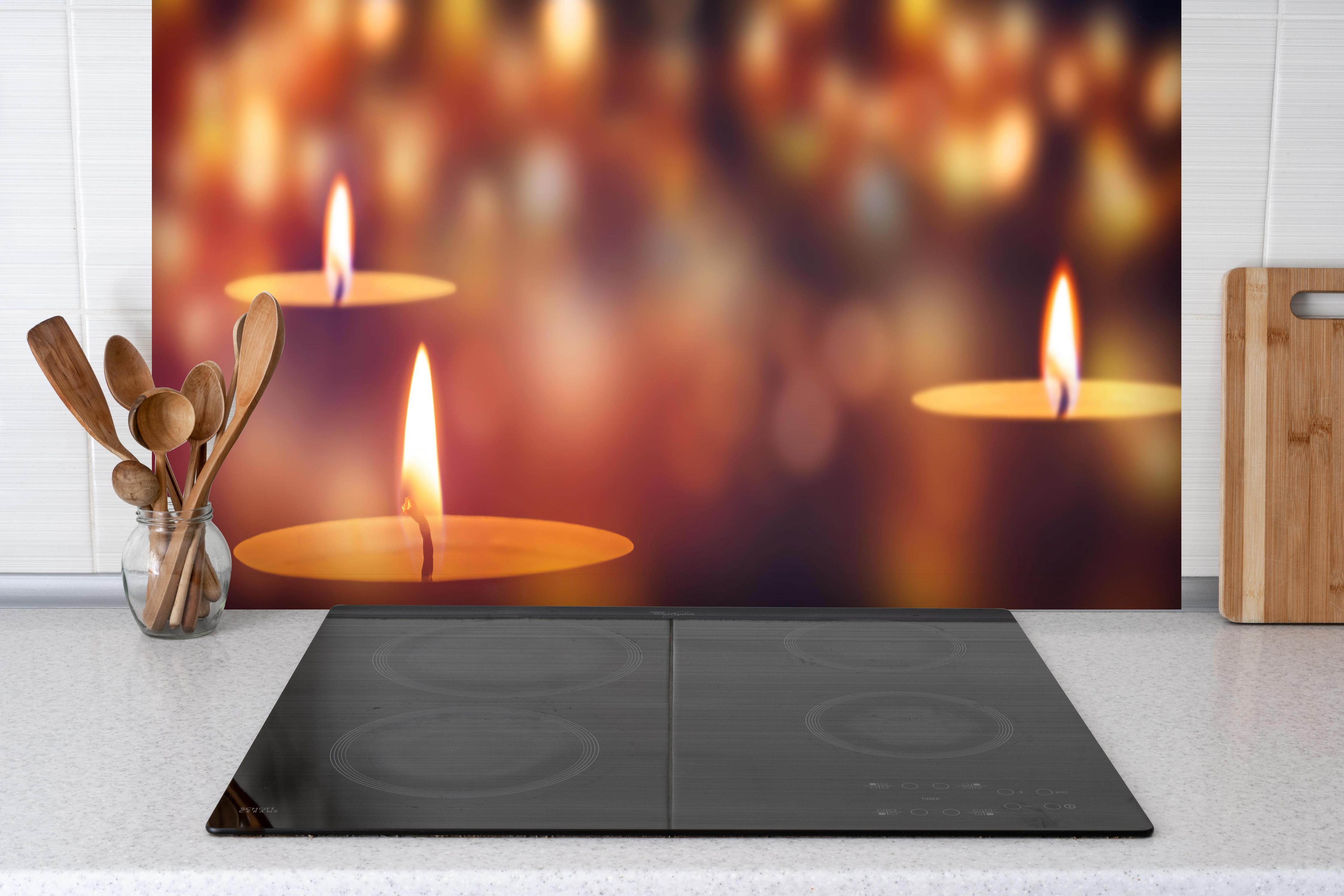 Spritzschutz - Den Teelichter bringen hinter einem Cerankochfeld zwischen Holz-Kochutensilien