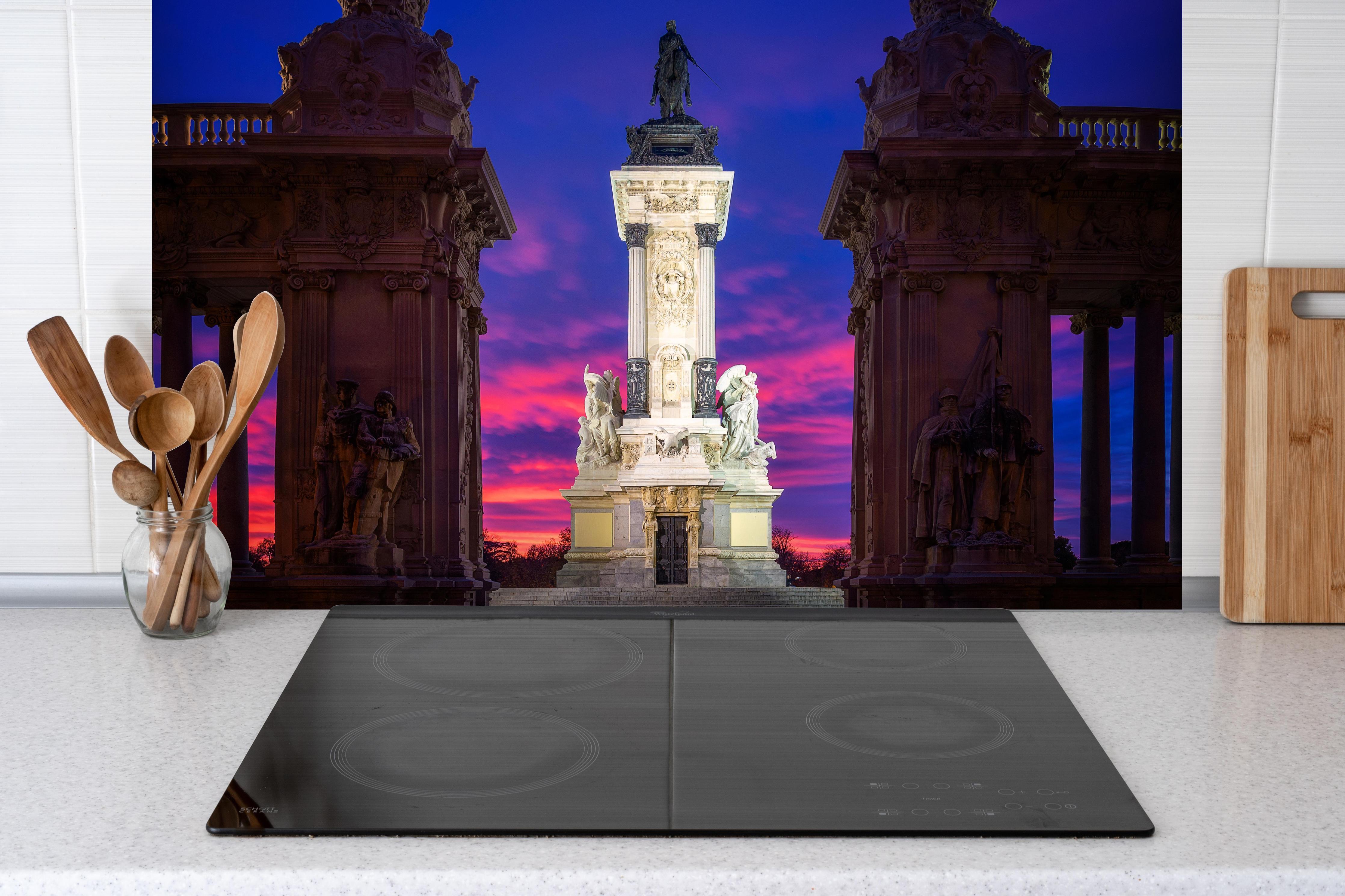 Spritzschutz - Denkmal für Alfonso XII bei rötlichem Himmel hinter einem Cerankochfeld zwischen Holz-Kochutensilien