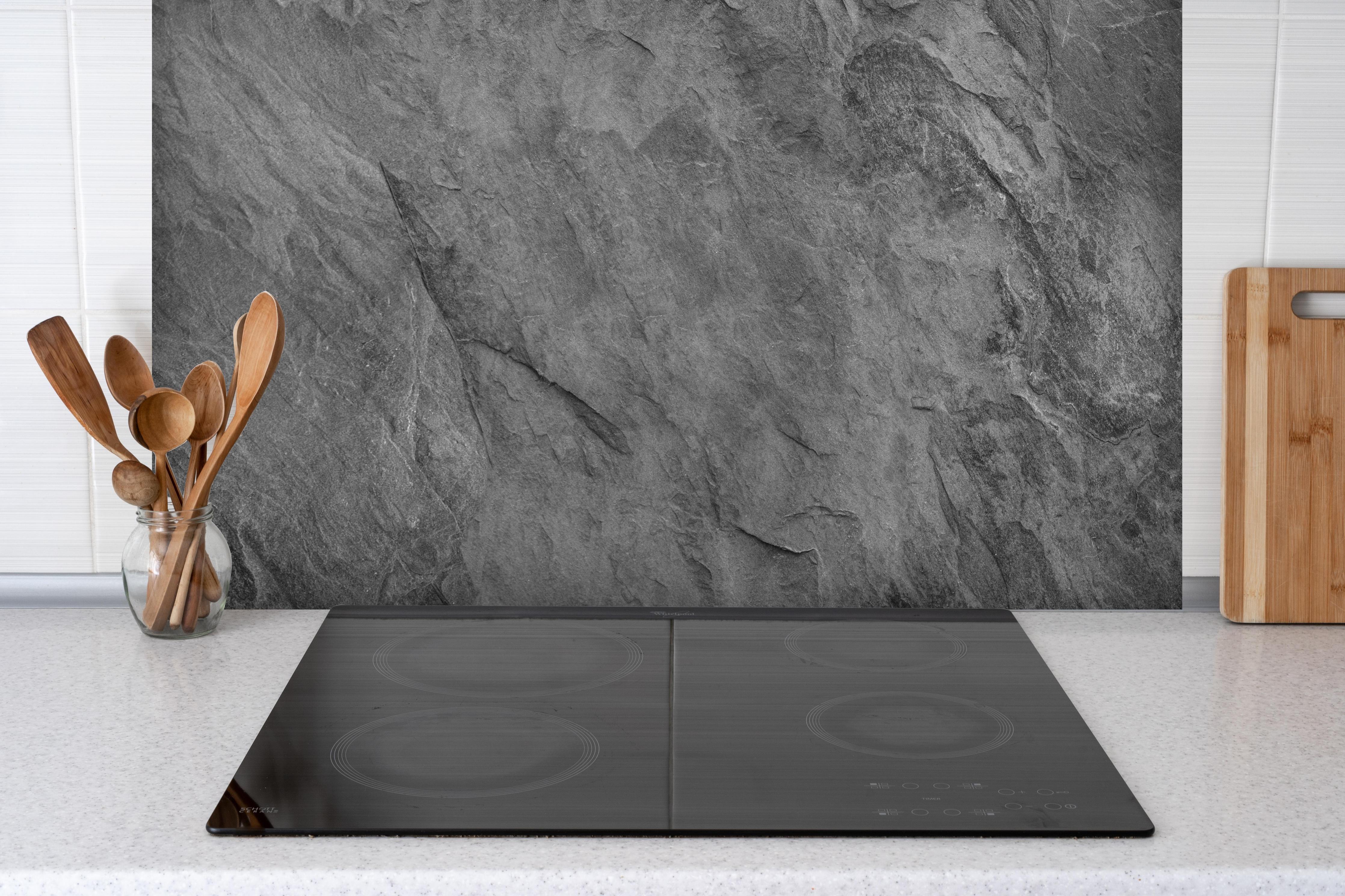 Spritzschutz - Dunkelgrauer Schiefer hinter einem Cerankochfeld zwischen Holz-Kochutensilien