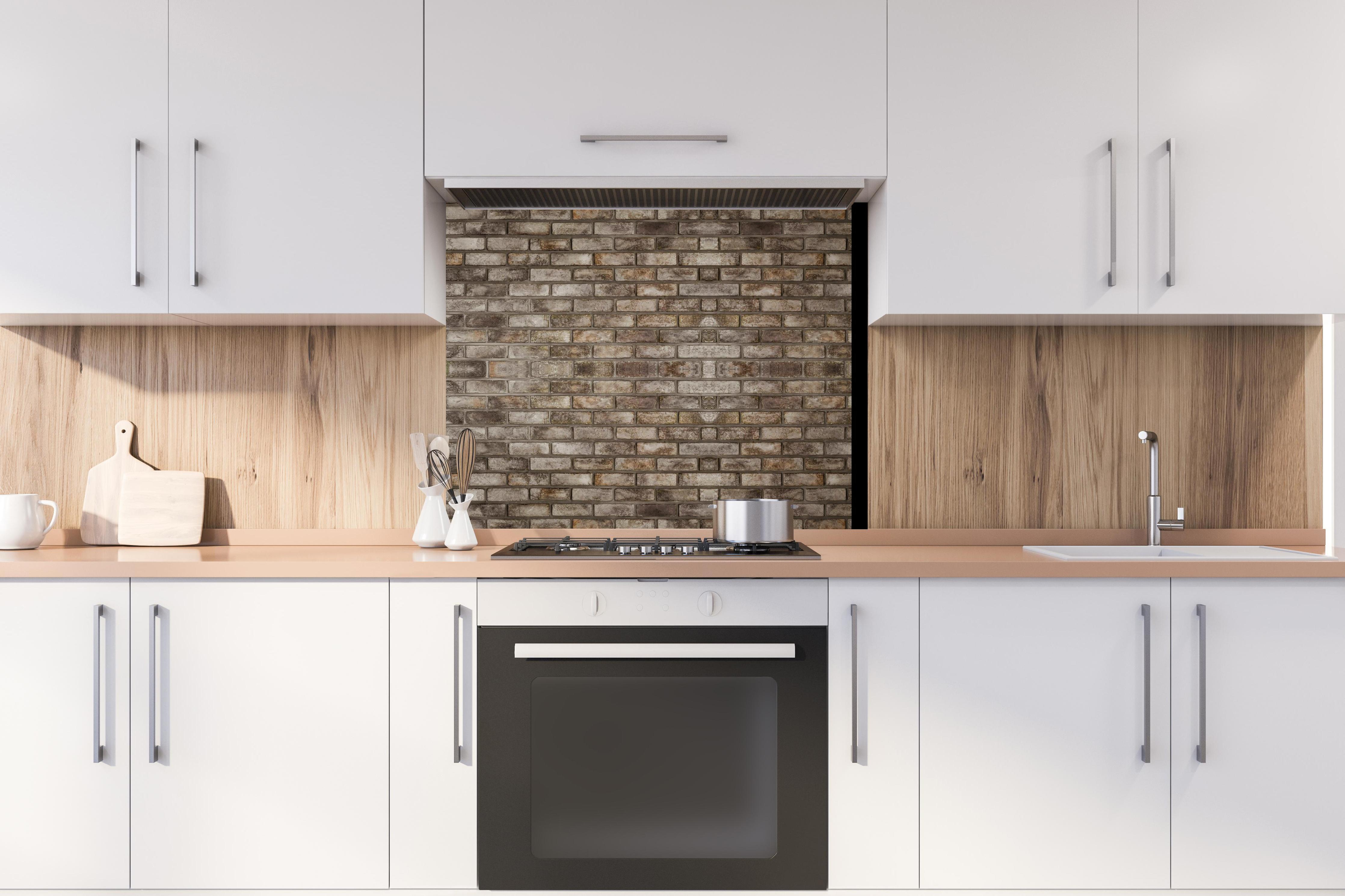 Spritzschutz - Dunkle Steinmauer hinter stilvollem Gasherd unter Dunstabzugshaube