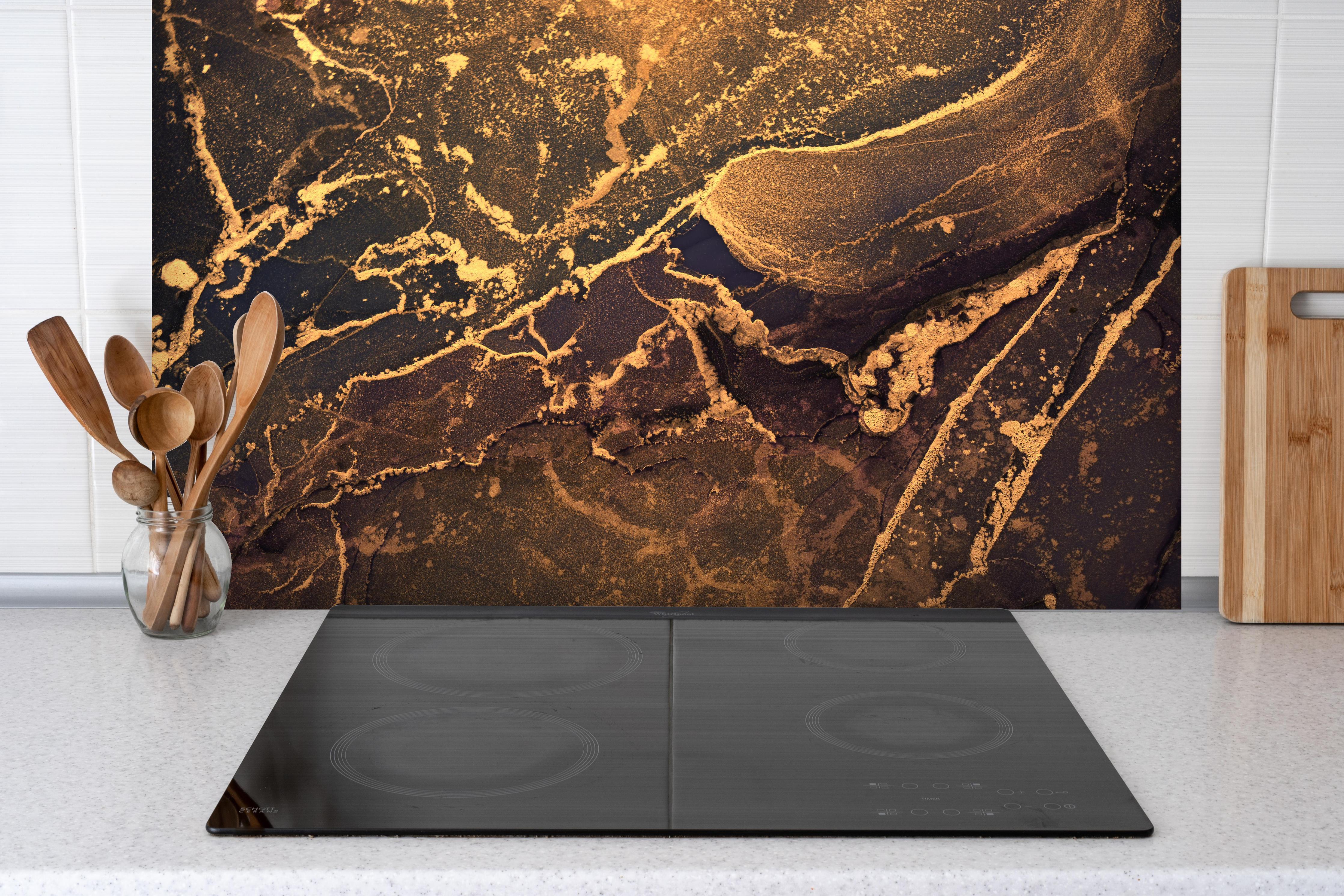 Spritzschutz - Dunkle Tinte mit Goldelementen hinter einem Cerankochfeld zwischen Holz-Kochutensilien
