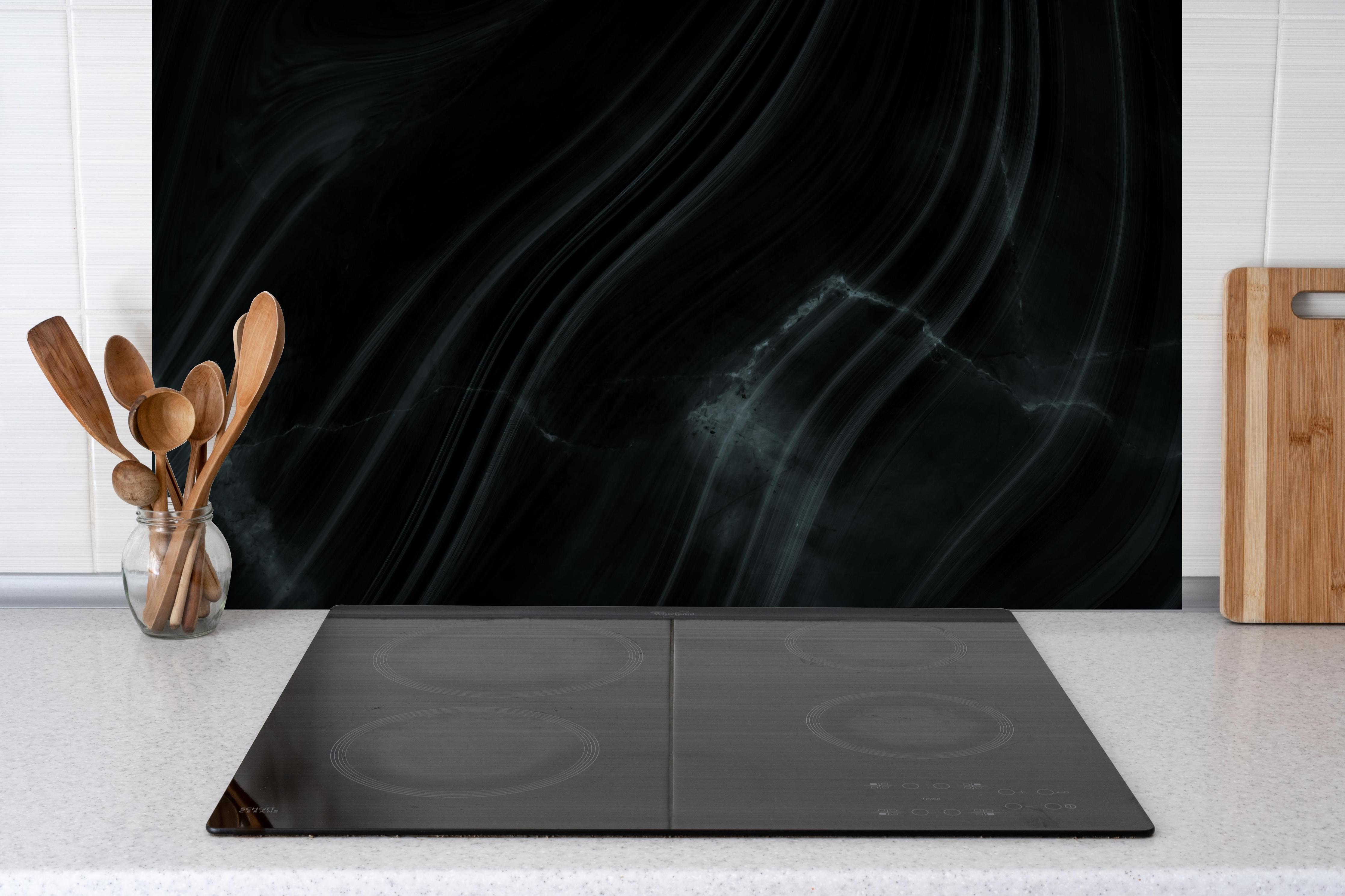 Spritzschutz - Dunkler klassischer Marmor hinter einem Cerankochfeld zwischen Holz-Kochutensilien