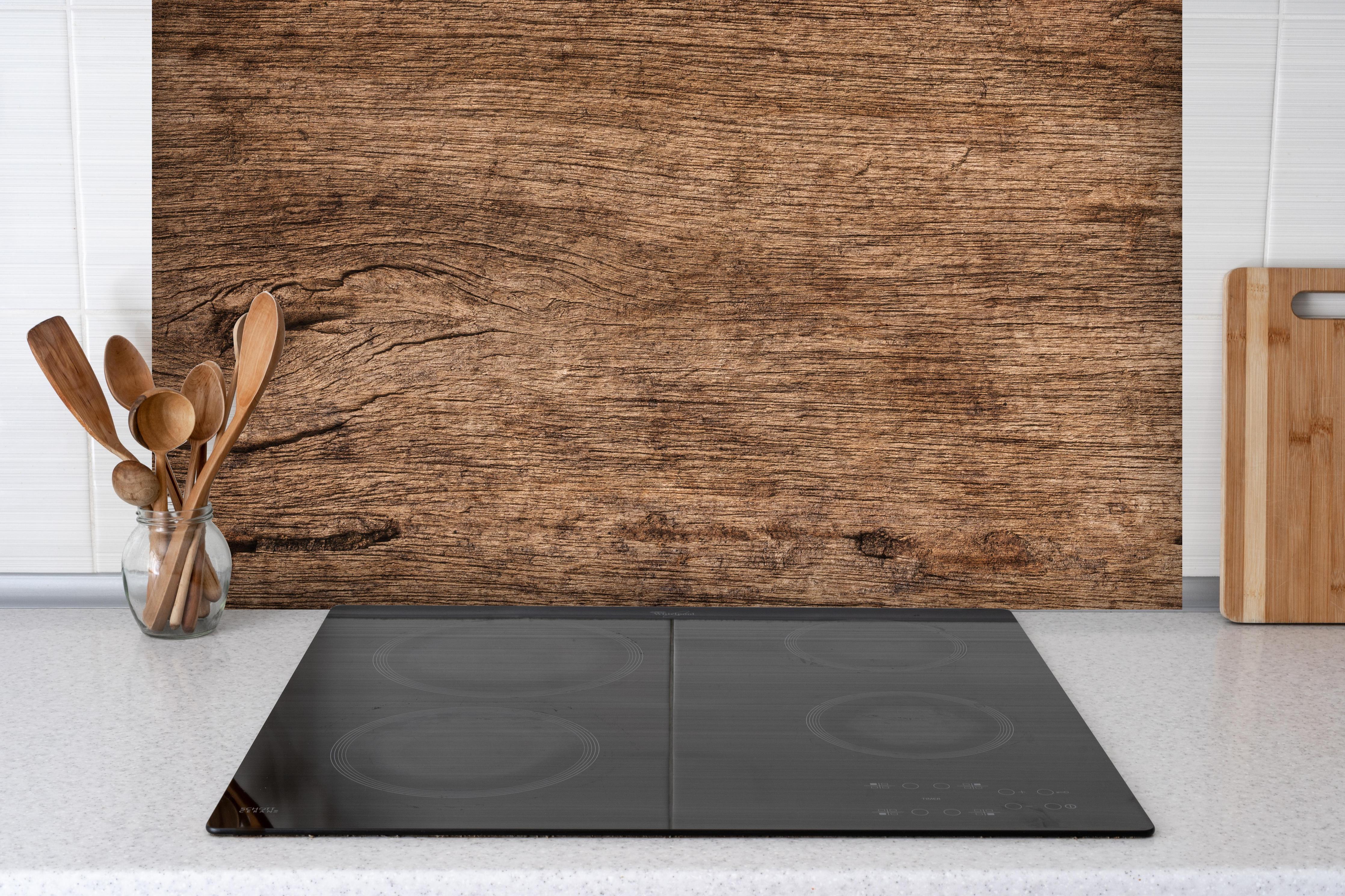 Spritzschutz - Dunkles verfallendes Holz hinter einem Cerankochfeld zwischen Holz-Kochutensilien