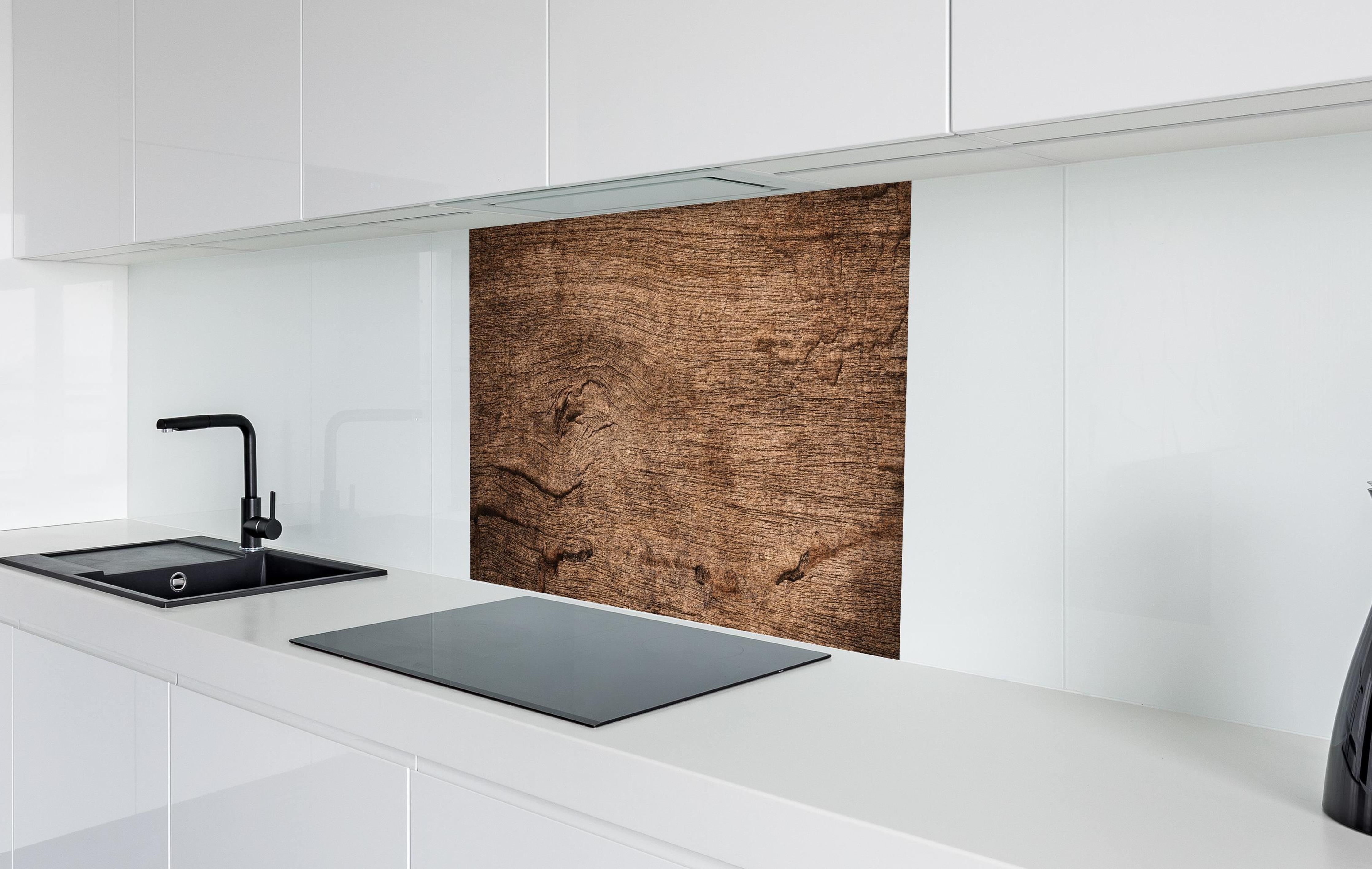Spritzschutz - Dunkles verfallendes Holz in weißer Hochglanz-Küche hinter einem Cerankochfeld