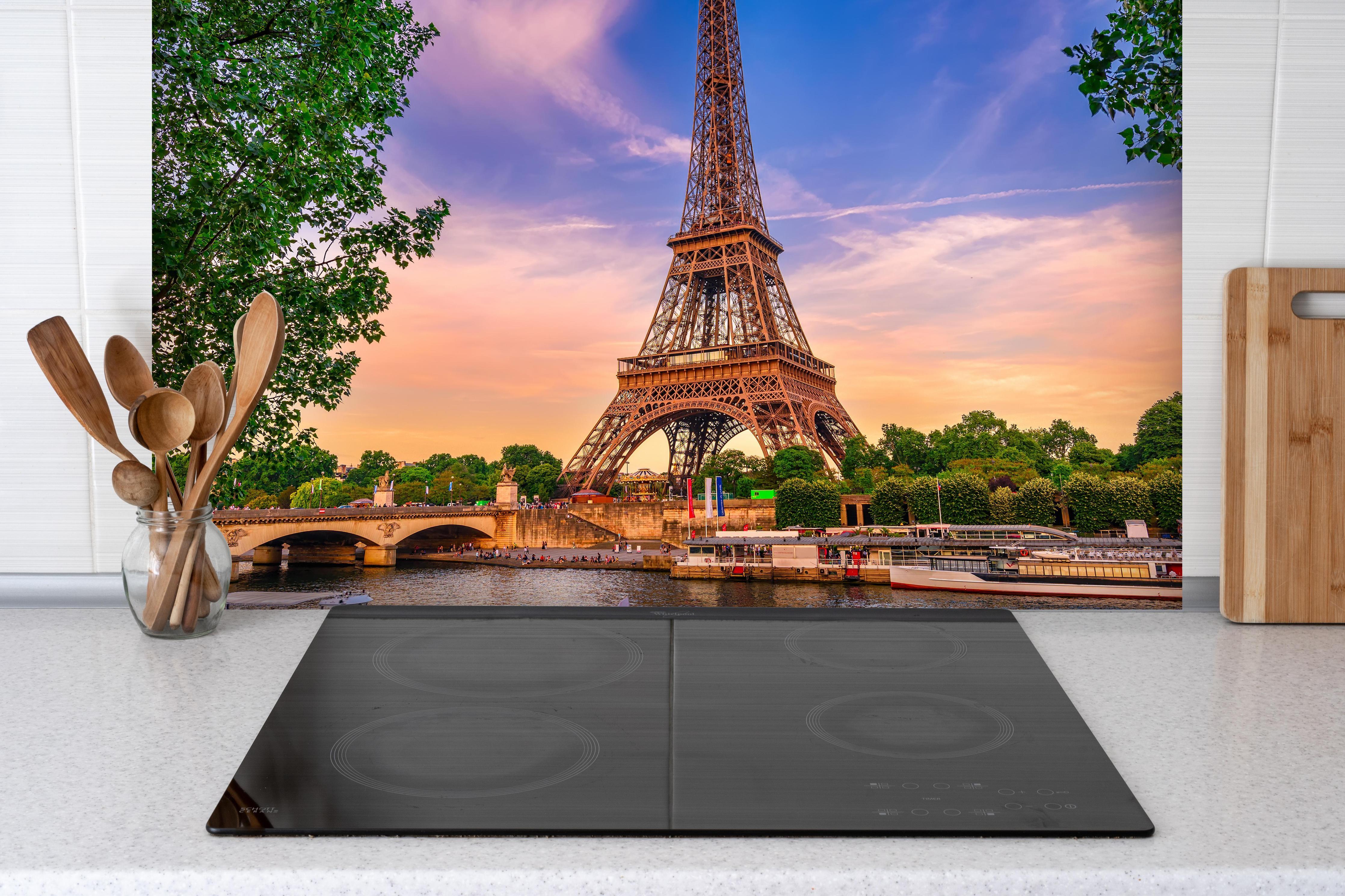Spritzschutz - Eiffelturm und Fluss Seine bei Sonnenuntergang hinter einem Cerankochfeld zwischen Holz-Kochutensilien