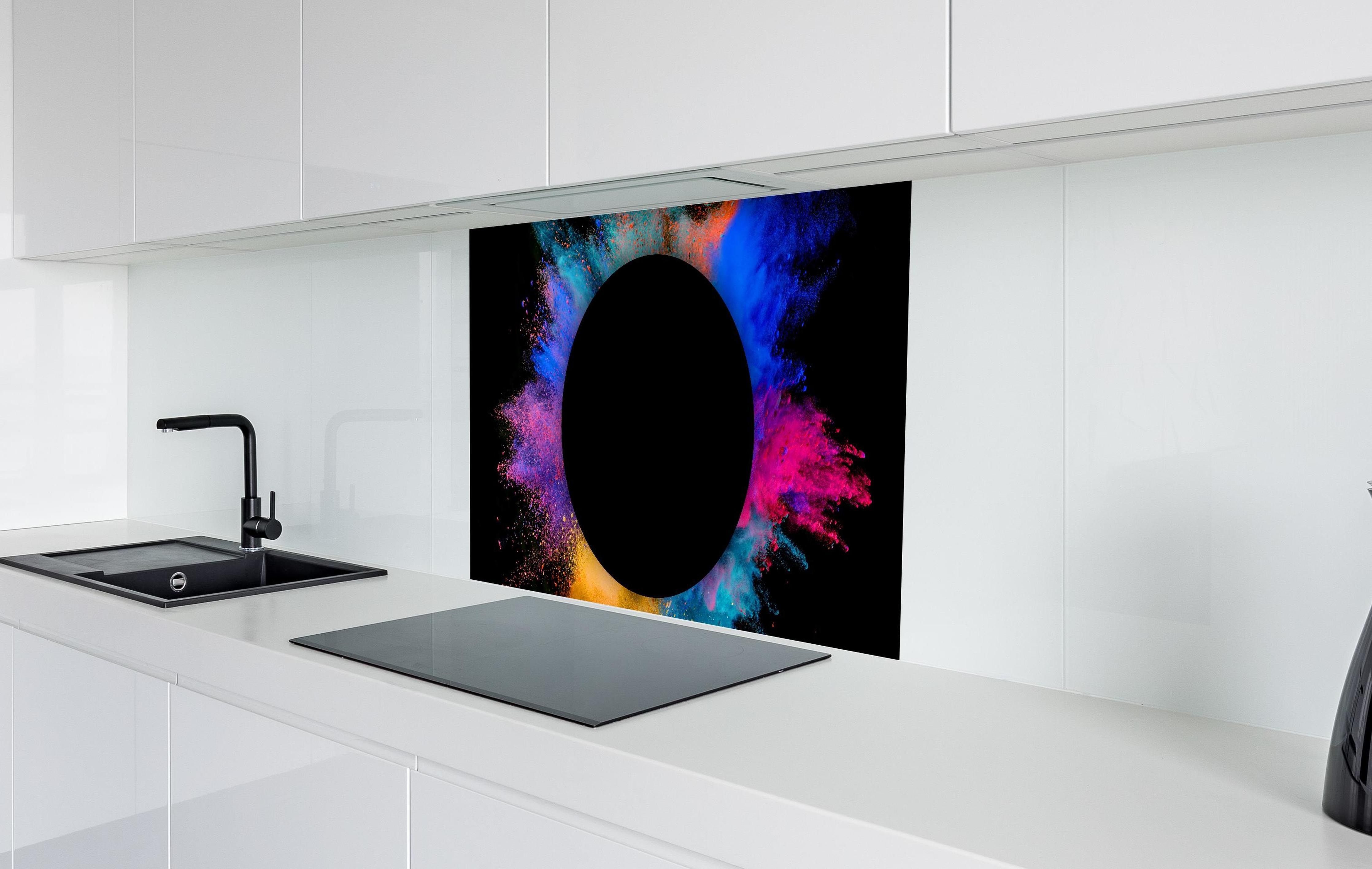 Spritzschutz - Explosion von farbigem Pulver mit schwarzem Kreis in weißer Hochglanz-Küche hinter einem Cerankochfeld