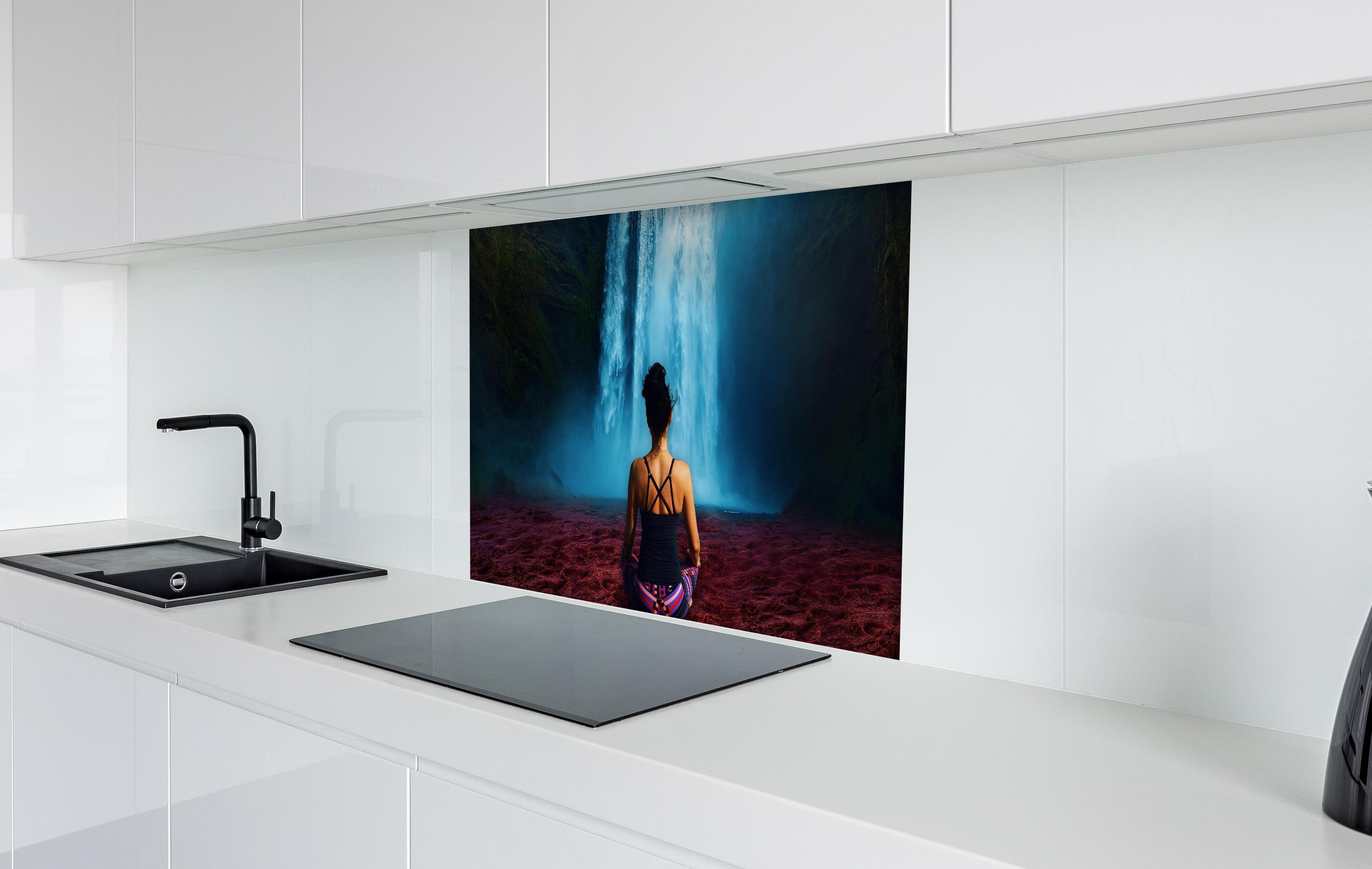 Spritzschutz - Frau meditierend vor traumhaften Wasserfall in weißer Hochglanz-Küche hinter einem Cerankochfeld