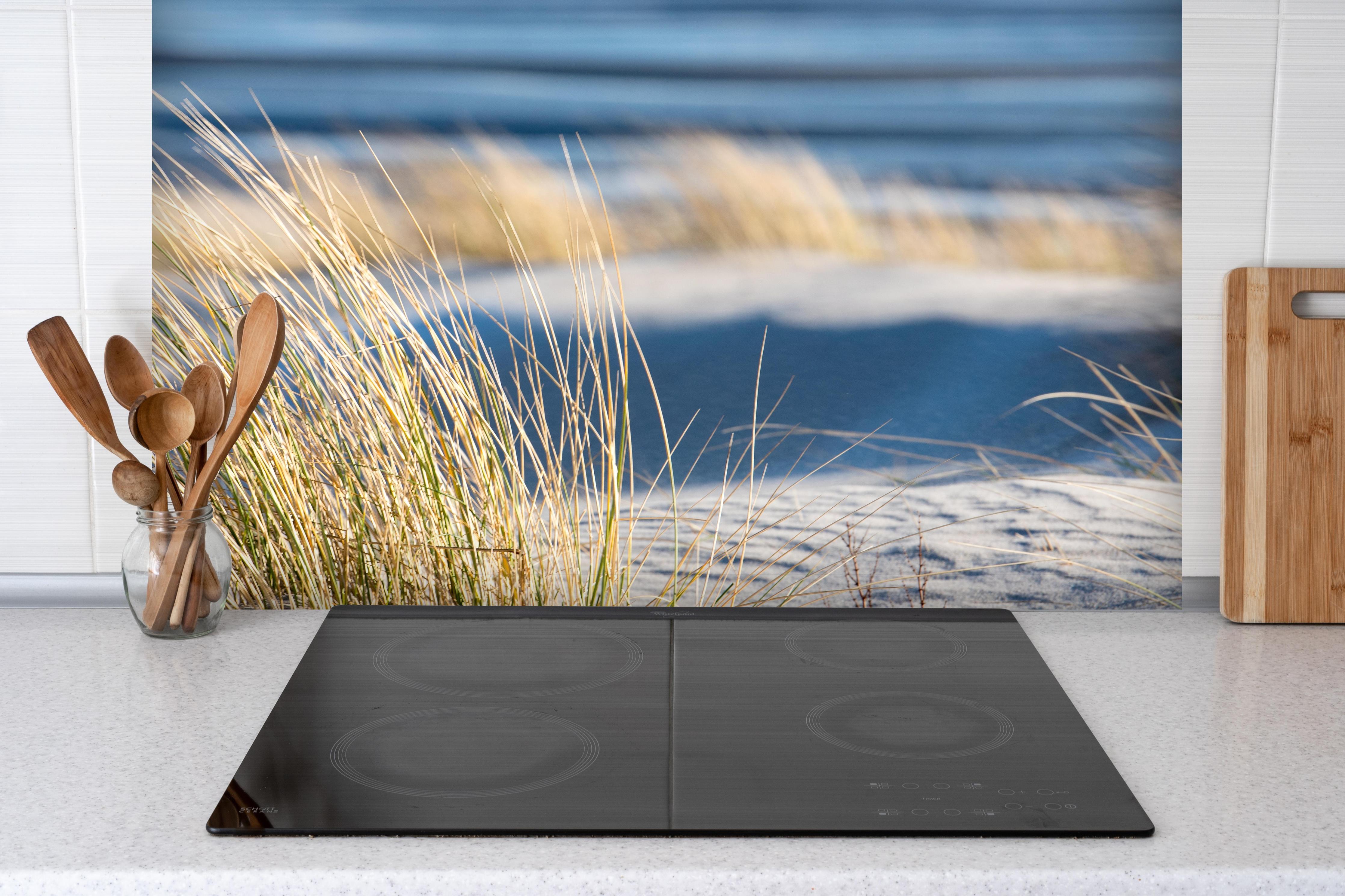 Spritzschutz - Friedlicher Strand - Nordsee hinter einem Cerankochfeld zwischen Holz-Kochutensilien