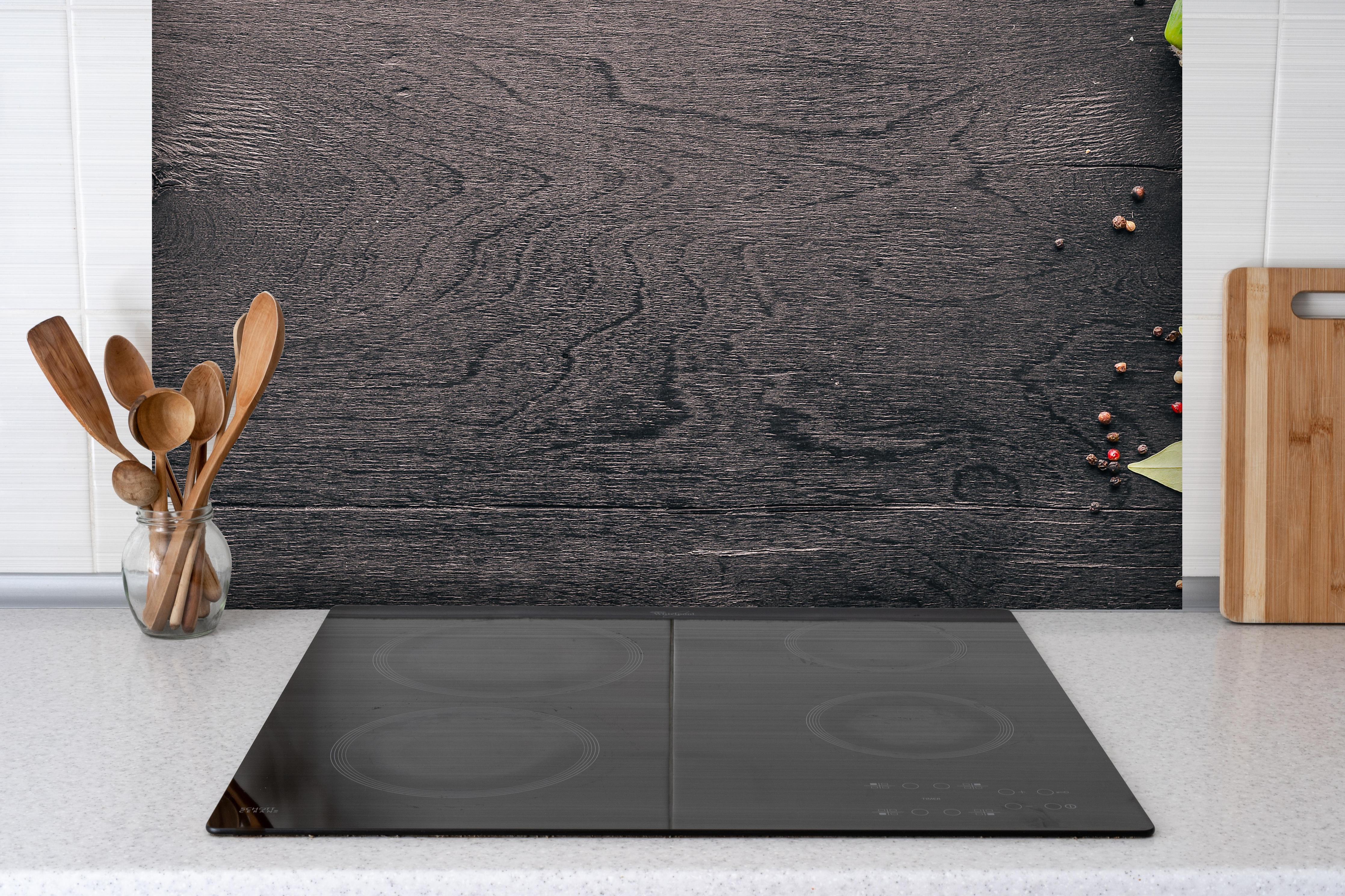 Spritzschutz - Frisches Gemüse auf hölzernen Kreidetafel hinter einem Cerankochfeld zwischen Holz-Kochutensilien