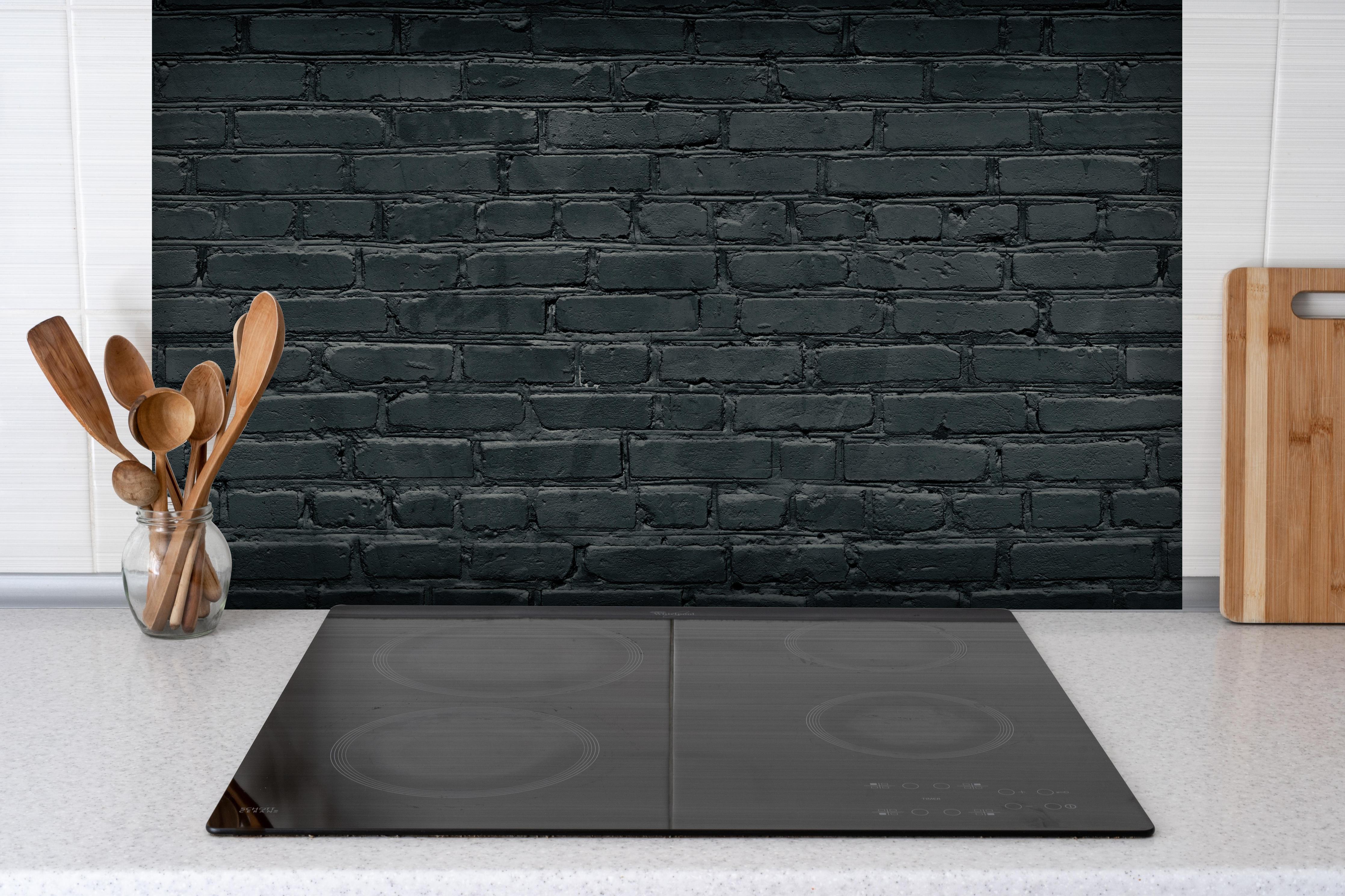 Spritzschutz - Gealtertes dunkles Mauerwerk hinter einem Cerankochfeld zwischen Holz-Kochutensilien