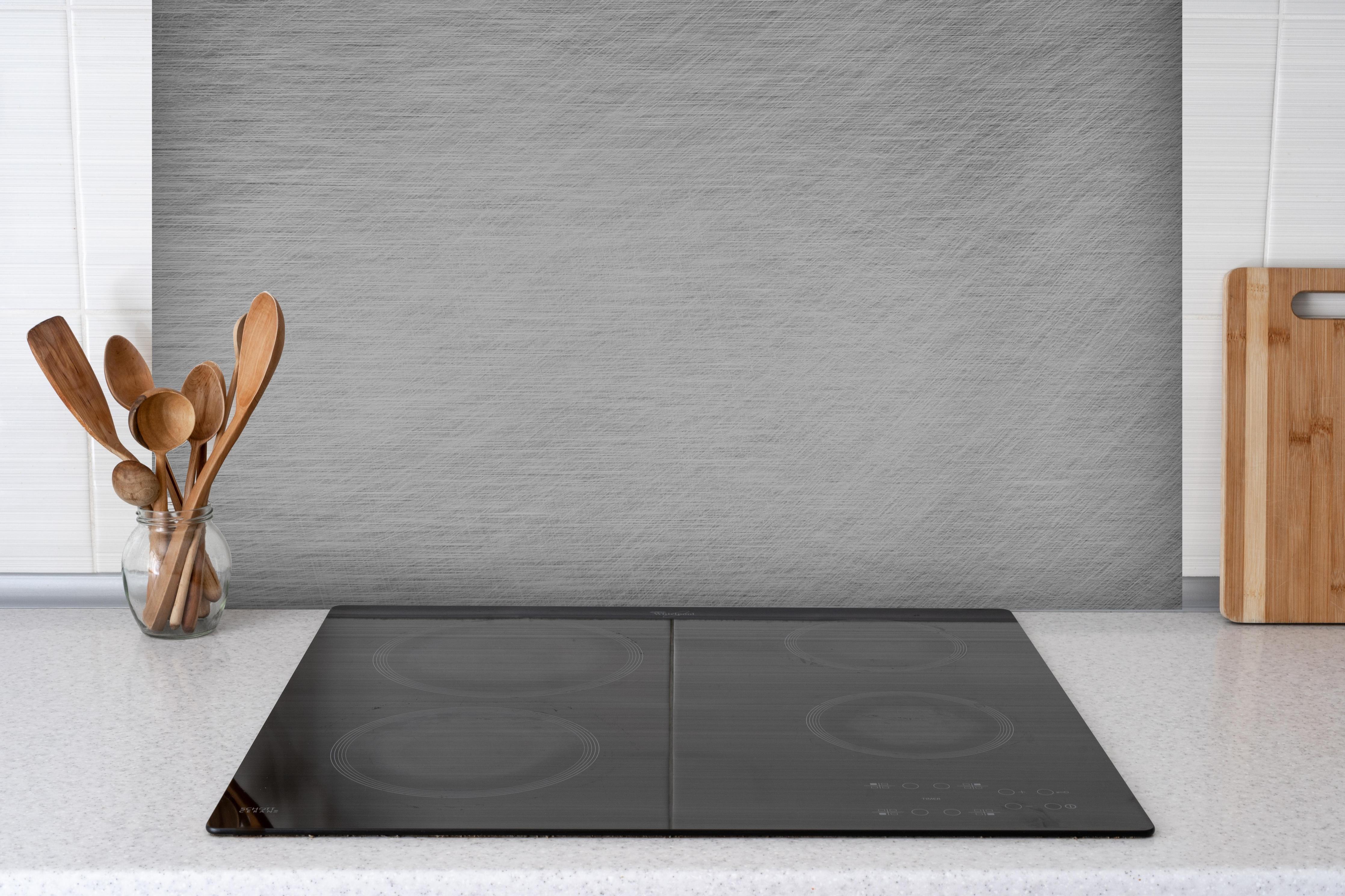 Spritzschutz - Gebürsteter Stahlblech Mix hinter einem Cerankochfeld zwischen Holz-Kochutensilien
