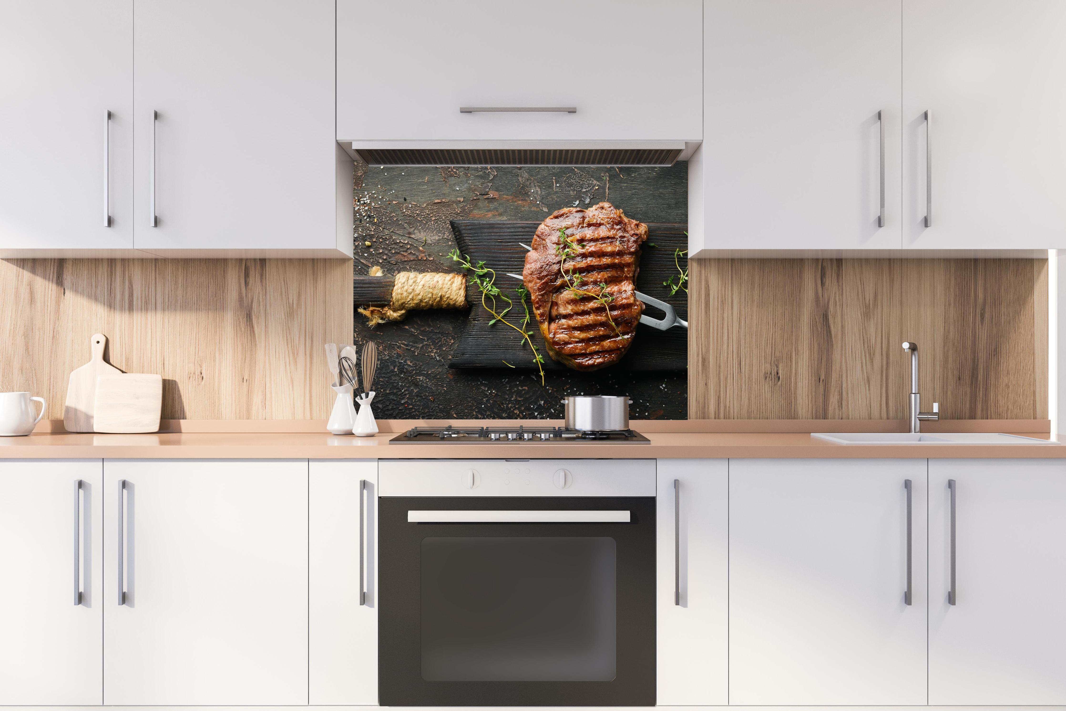 Spritzschutz - Gegrilltes Ribeye auf Holzplatte hinter stilvollem Gasherd unter Dunstabzugshaube