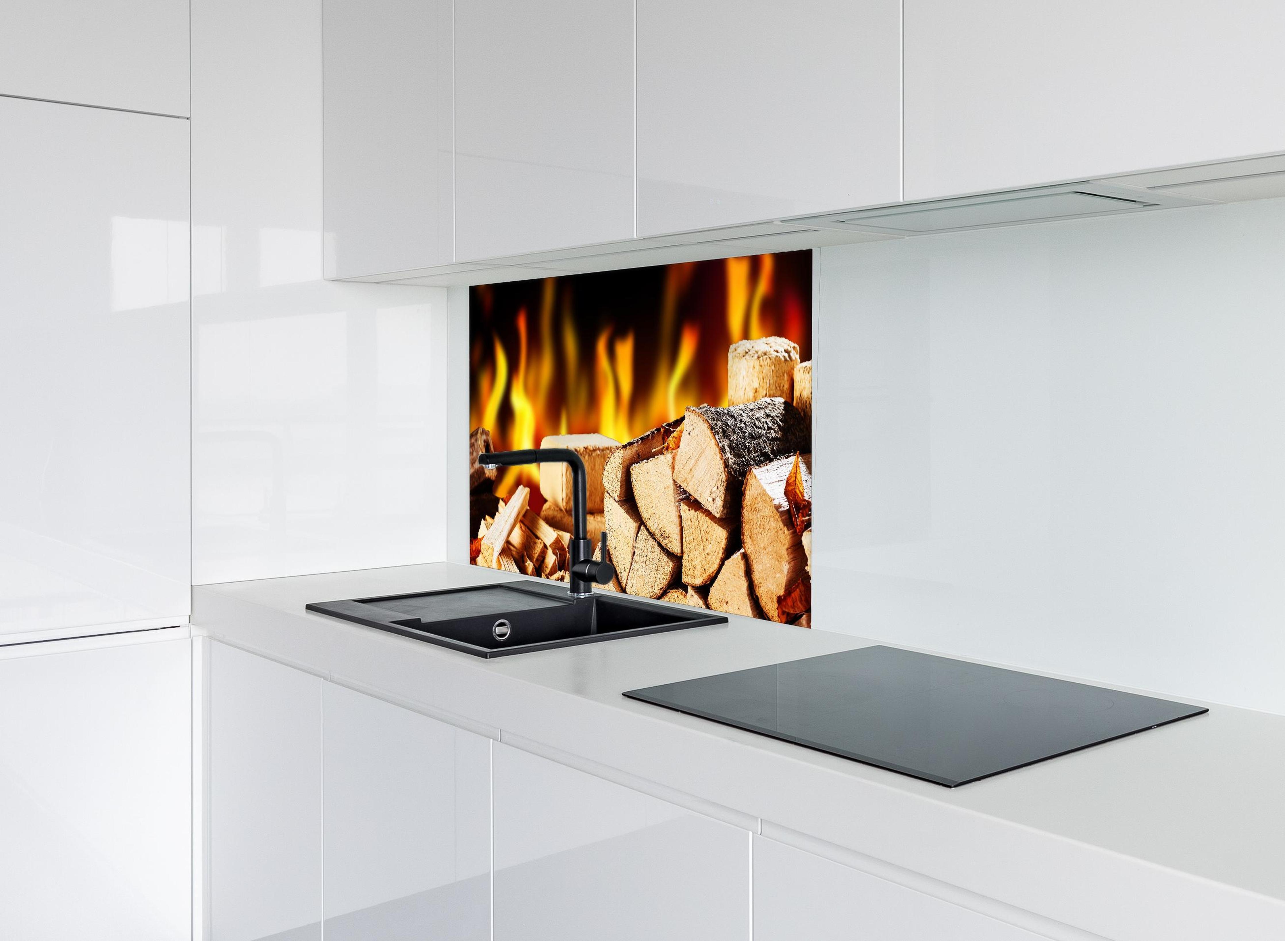 Spritzschutz - Gestapelte Holzscheite vor brennendem Feuer hinter modernem schwarz-matten Spülbecken in weißer Hochglanz-Küche