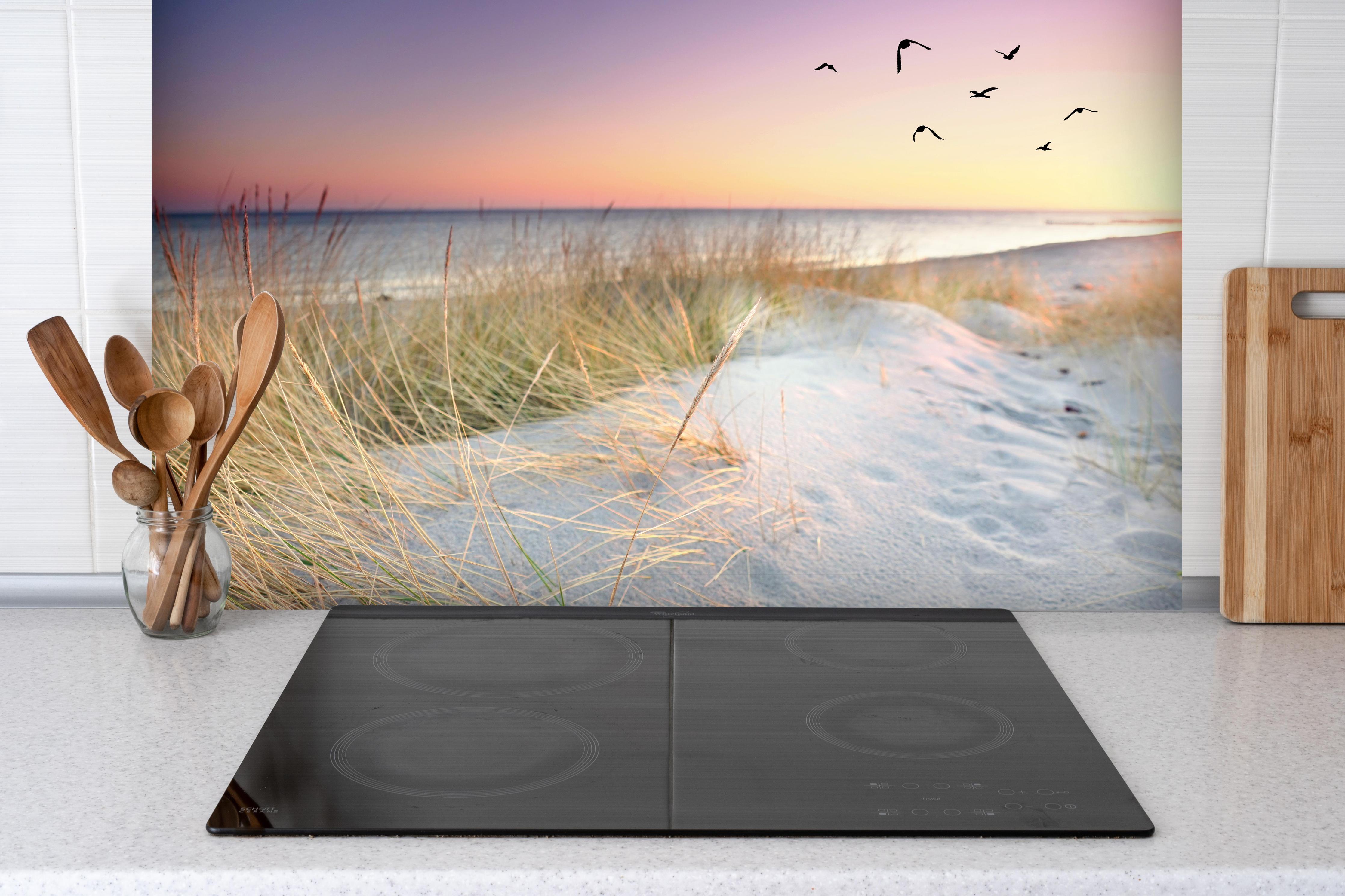 Spritzschutz - Goldenes Sonnenlicht an der Ostsee hinter einem Cerankochfeld zwischen Holz-Kochutensilien