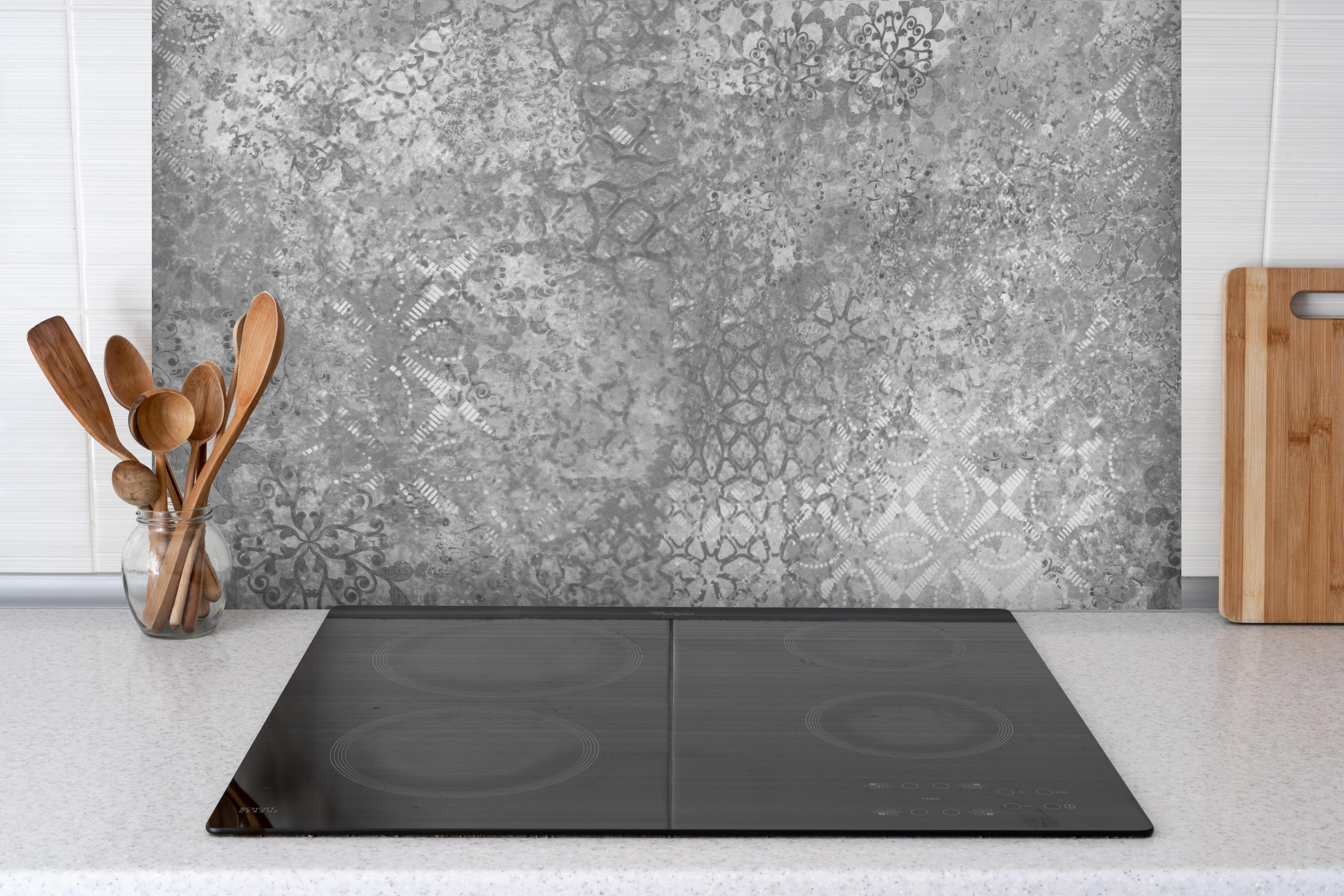 Spritzschutz - Gräuliche Patchwork Fliesen hinter einem Cerankochfeld zwischen Holz-Kochutensilien